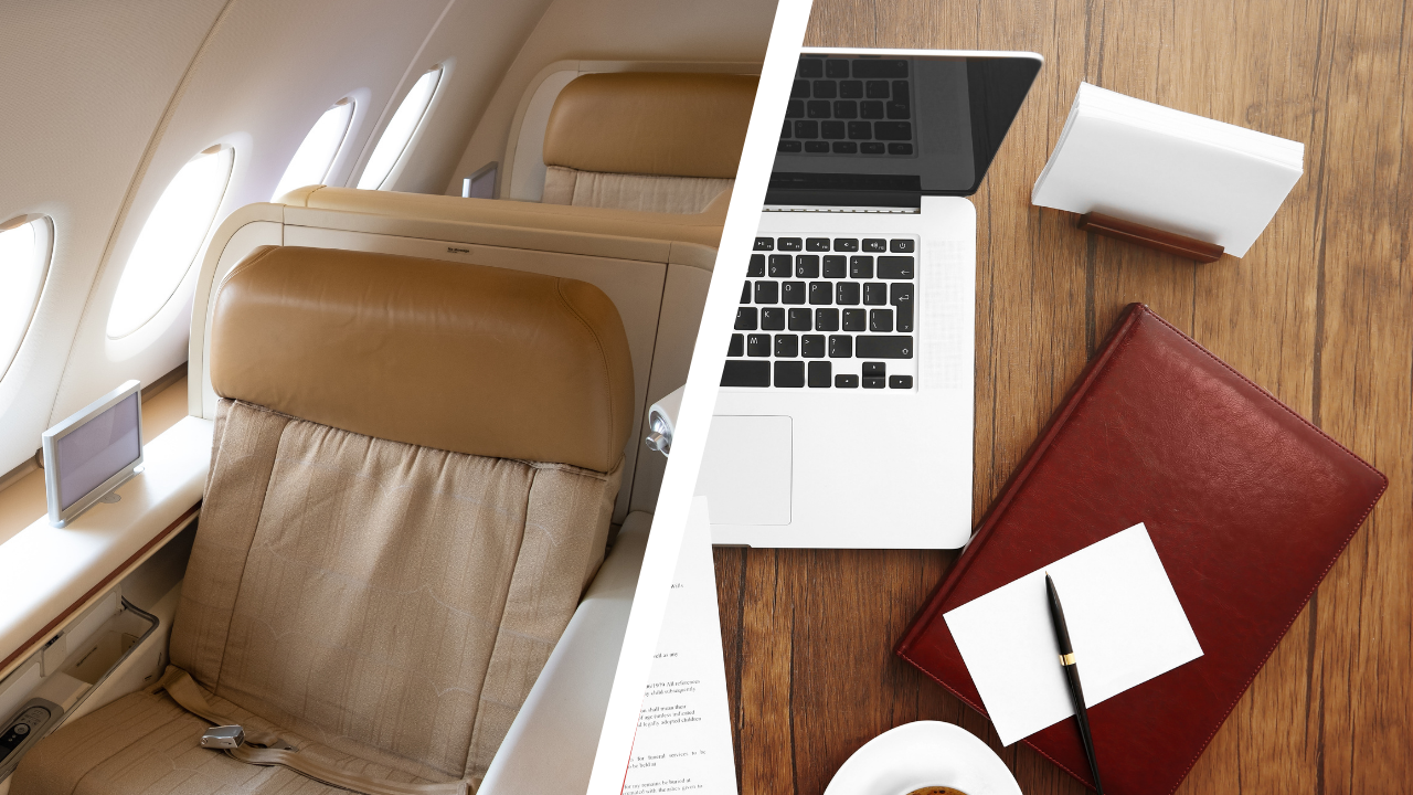 Airplane seat with beige leather headrest and seatback screen on window side, and a workspace with a laptop, notebook, pen, and cup of coffee on a wooden table.