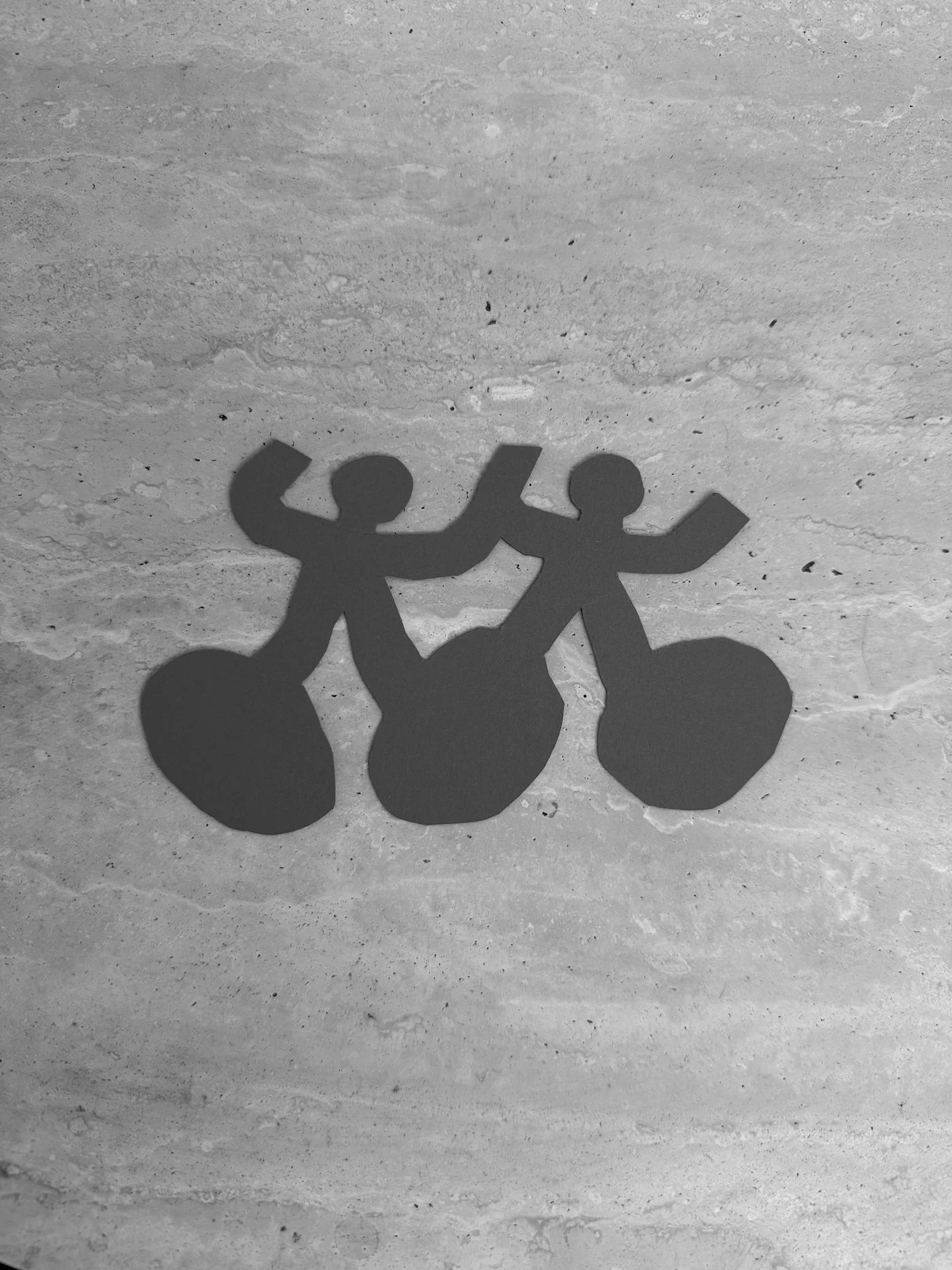 Silhouette of three people holding hands in a line, cast as shadows on a textured floor.