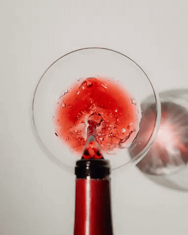 A glass of red wine being poured from a bottle with a clear background.