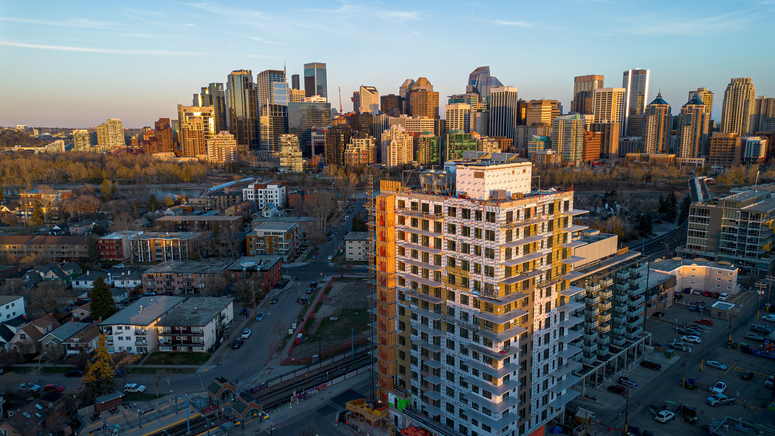 City skyline with various high-rise buildings and a construction site with a tall, partially built building in the foreground. Kit Kensington