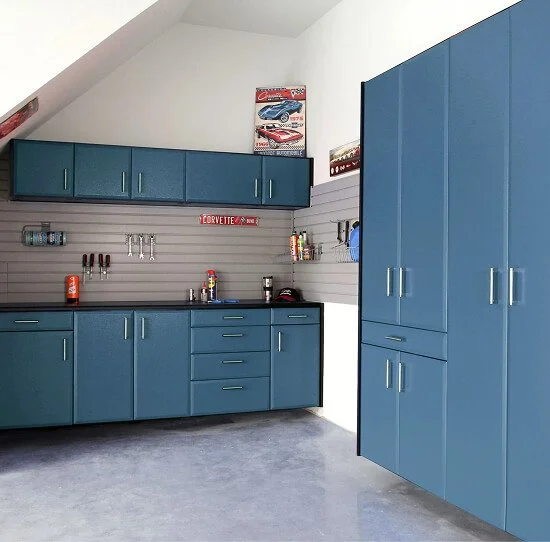 Garage with blue cabinets, wall hooks, and Corvette posters.