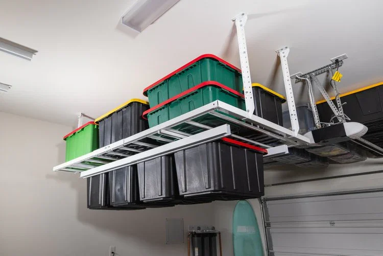 Garage ceiling with storage bins on metal racks, including green, yellow, red, and black containers.