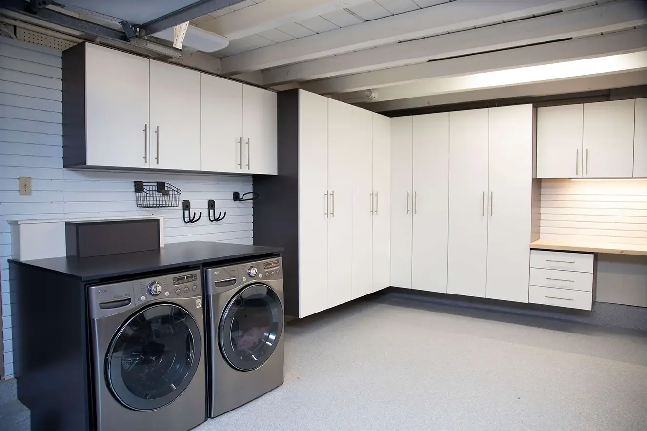 Laundry room with washer and dryer, white cabinets, wall hooks, and a workbench.