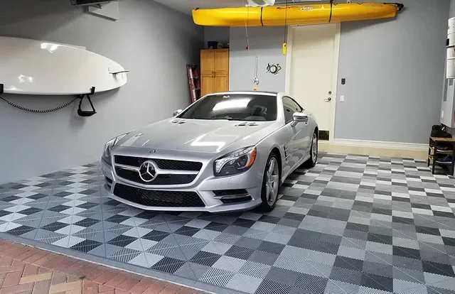 Silver Mercedes-Benz car parked in a well-organized garage with a checkered floor, a yellow kayak mounted overhead, and storage cabinets along the wall.
