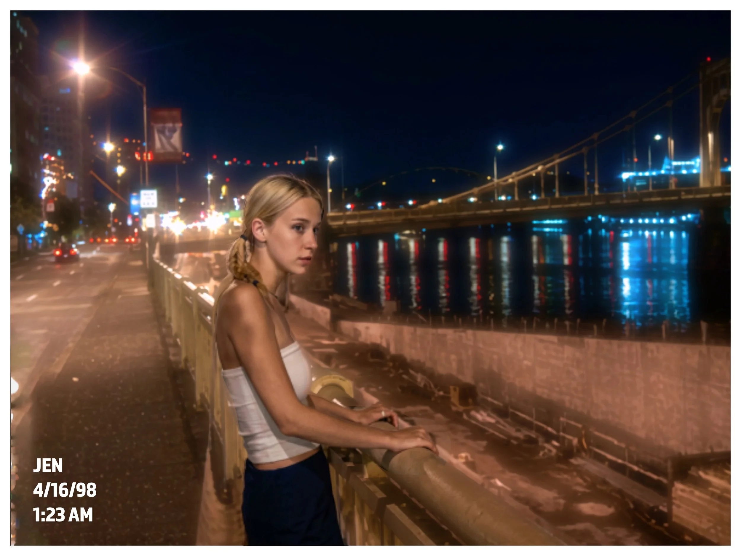 A young woman with blonde hair styled in braids, wearing a white tank top, sitting on a bench at night by a river with a city bridge in the background illuminated with colorful lights. City buildings and streetlights are visible across the river.