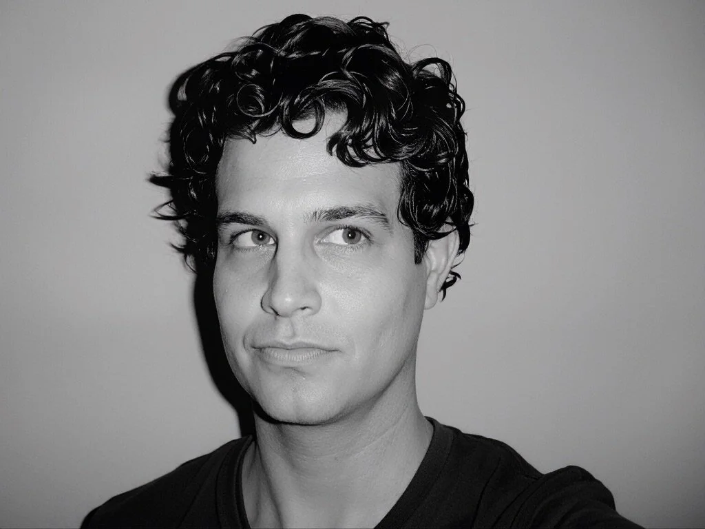 Black and white portrait of a young man with curly hair, looking slightly to the side.