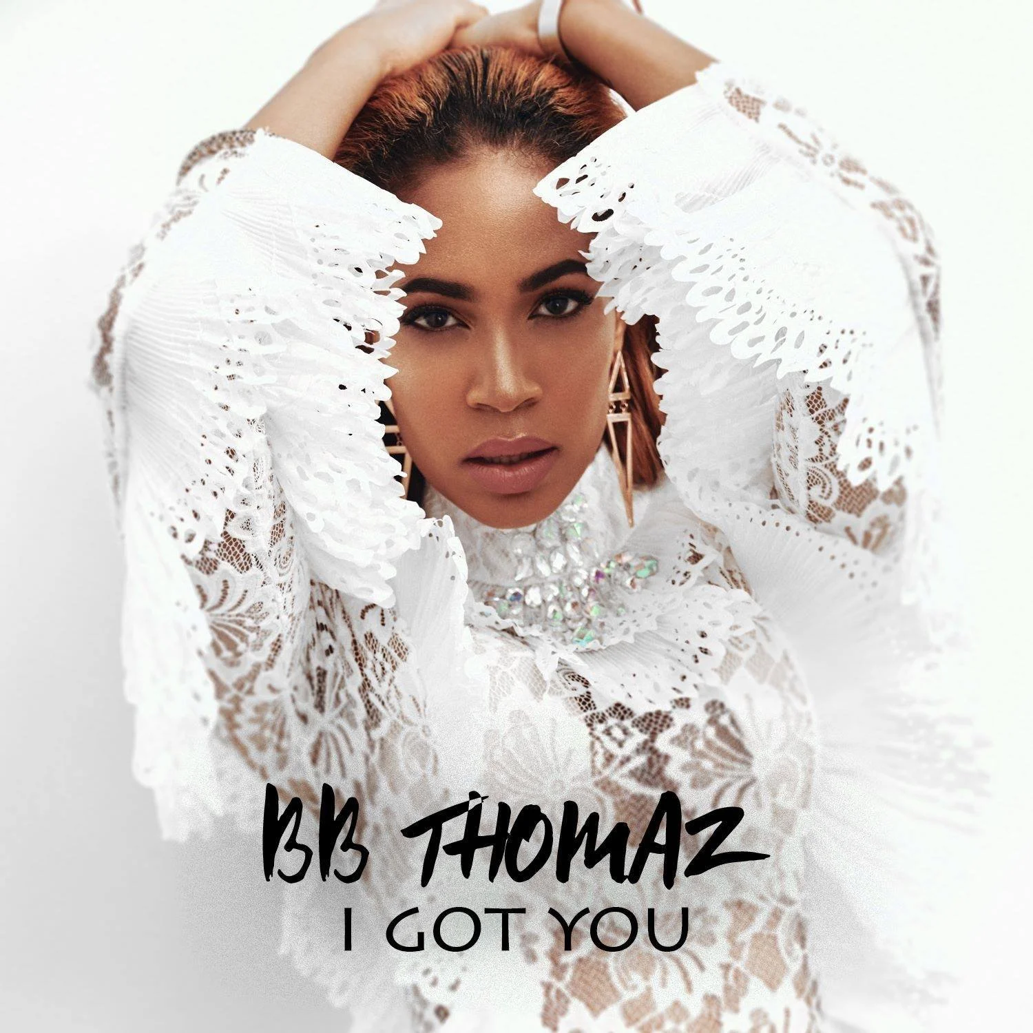 A woman with dark eyebrows and lips, wearing a white lace dress with large earrings and a necklace, holding her hands above her head. The image has the text 'B3 THOMAZ I GOT YOU' at the bottom.