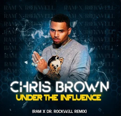 Chris Brown posing with a serious expression, wearing a gray sweater with a teddy bear graphic, in front of a blue background with the text 'RAM X ROCKWELL' repeatedly, and the words 'Chris Brown Under the Influence' with a remix note.