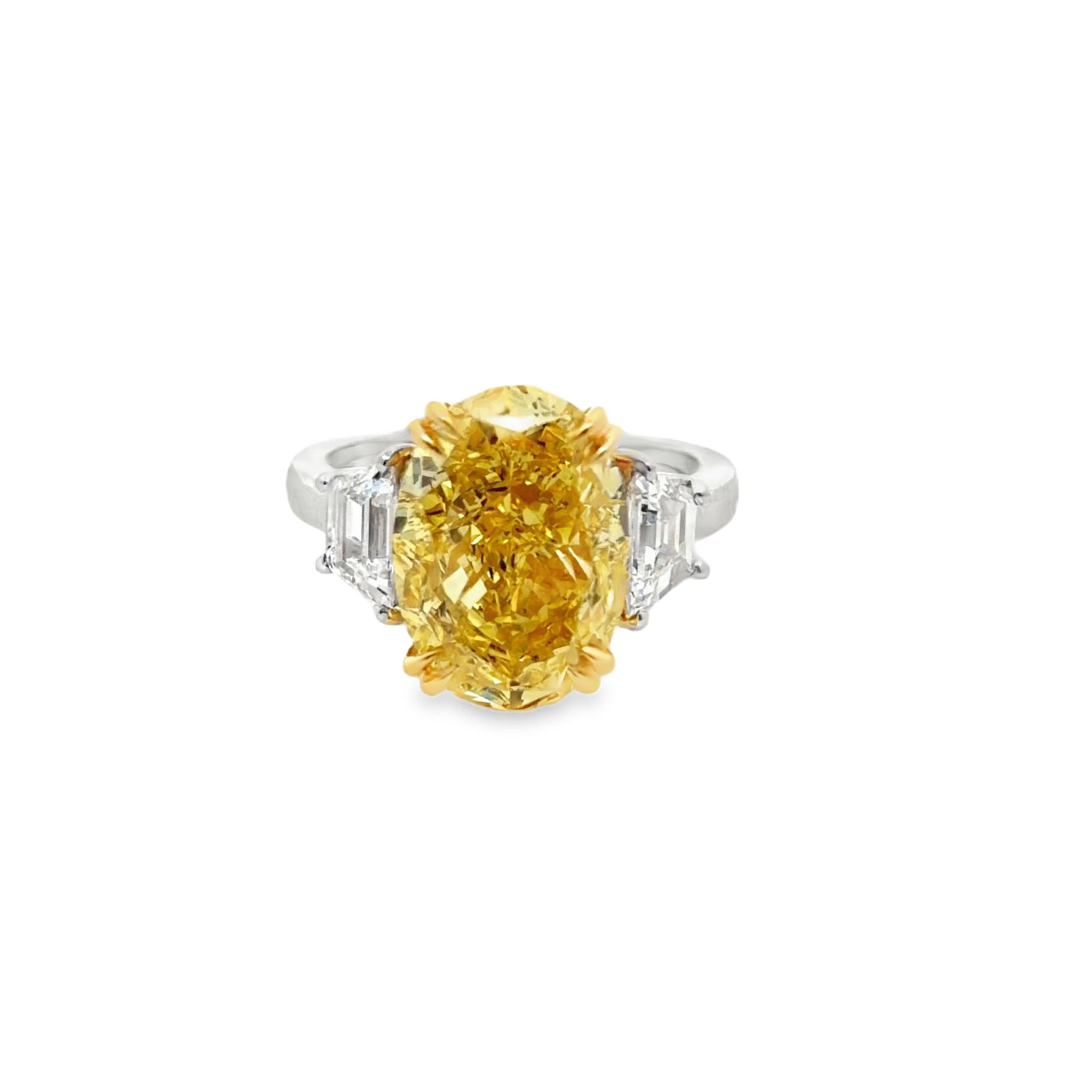 Diamond ring with a large yellow gemstone and rectangular clear side stones on a white background.