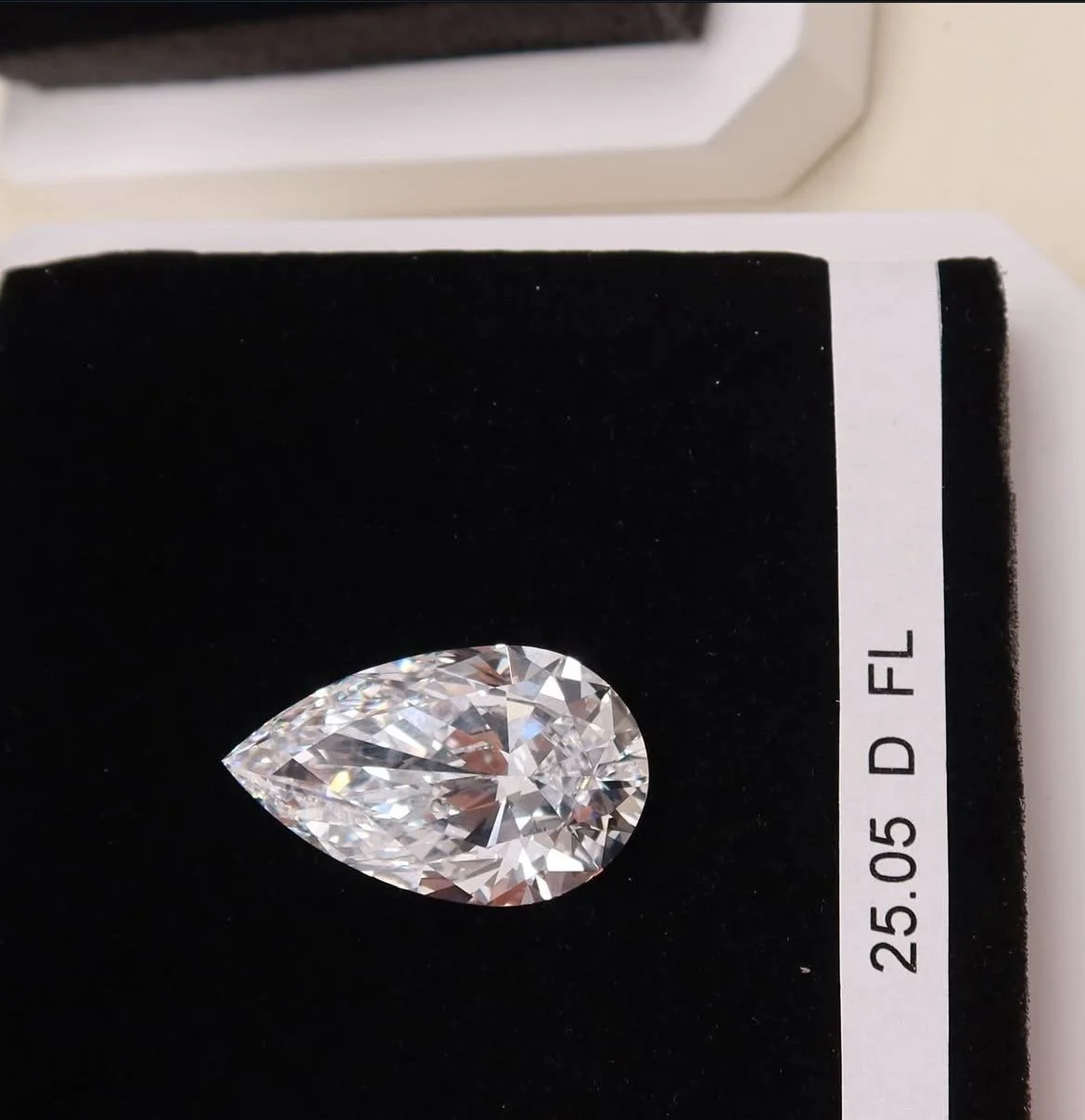 A large, pear-shaped diamond displayed on a black velvet display with a white label indicating its weight of 25.05 carats and clarity grade D Fl.