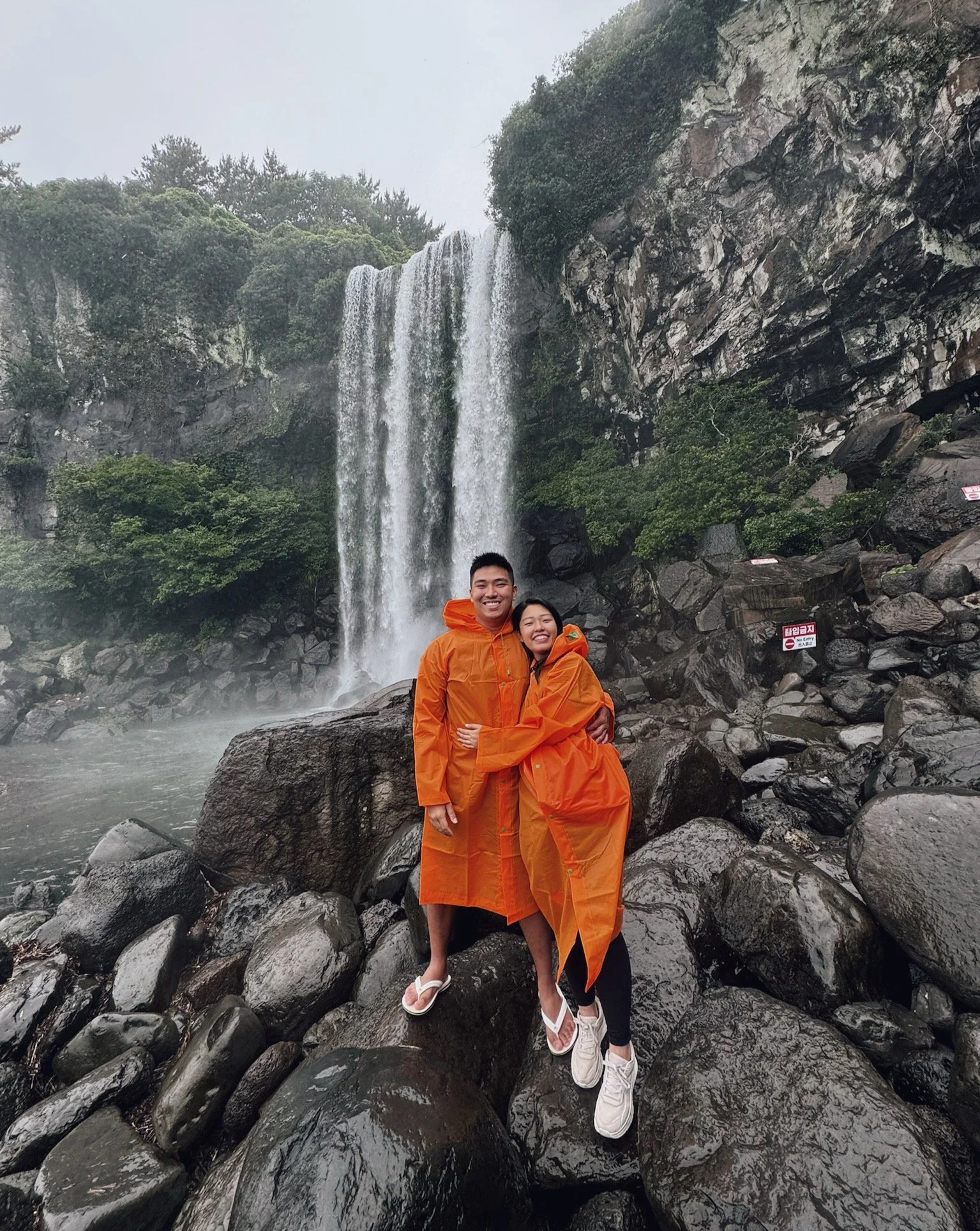 Then came Korea, 🇰🇷 where they journeyed through Jeju, chased waterfalls, braved the rain, and somehow still looked like two very happy orange traffic cones. 🍊 🍊 