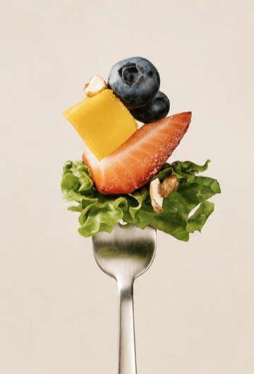A fork with a bite-sized salad consisting of lettuce, cheese, strawberries, blueberries, banana, and nuts.