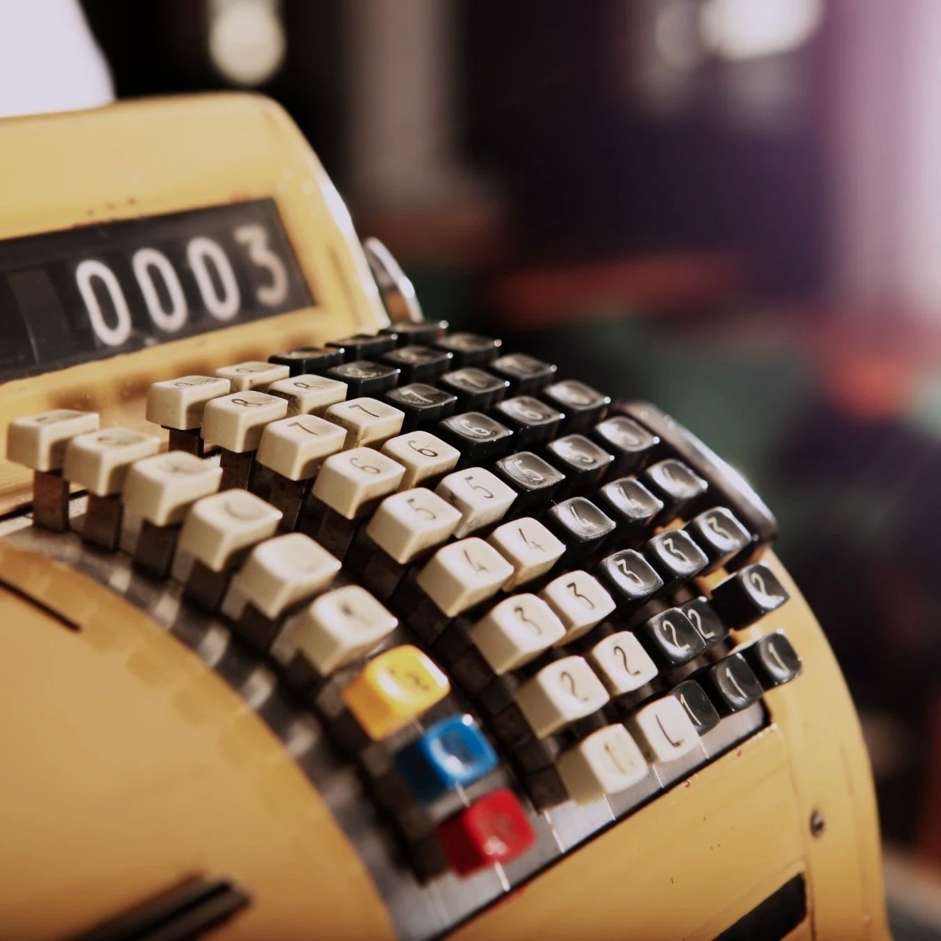 A vintage mechanical calculator with rows of cream and black keys and a display showing '0003'.