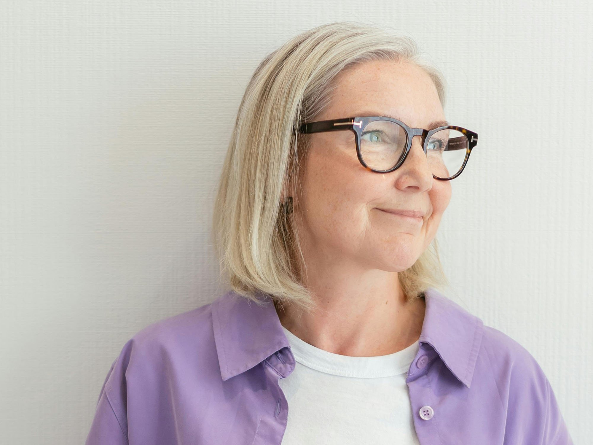 Woman with glasses looking thoughtfully off camera representing support, advice, and treatment options to help navigate menopause with confidence.