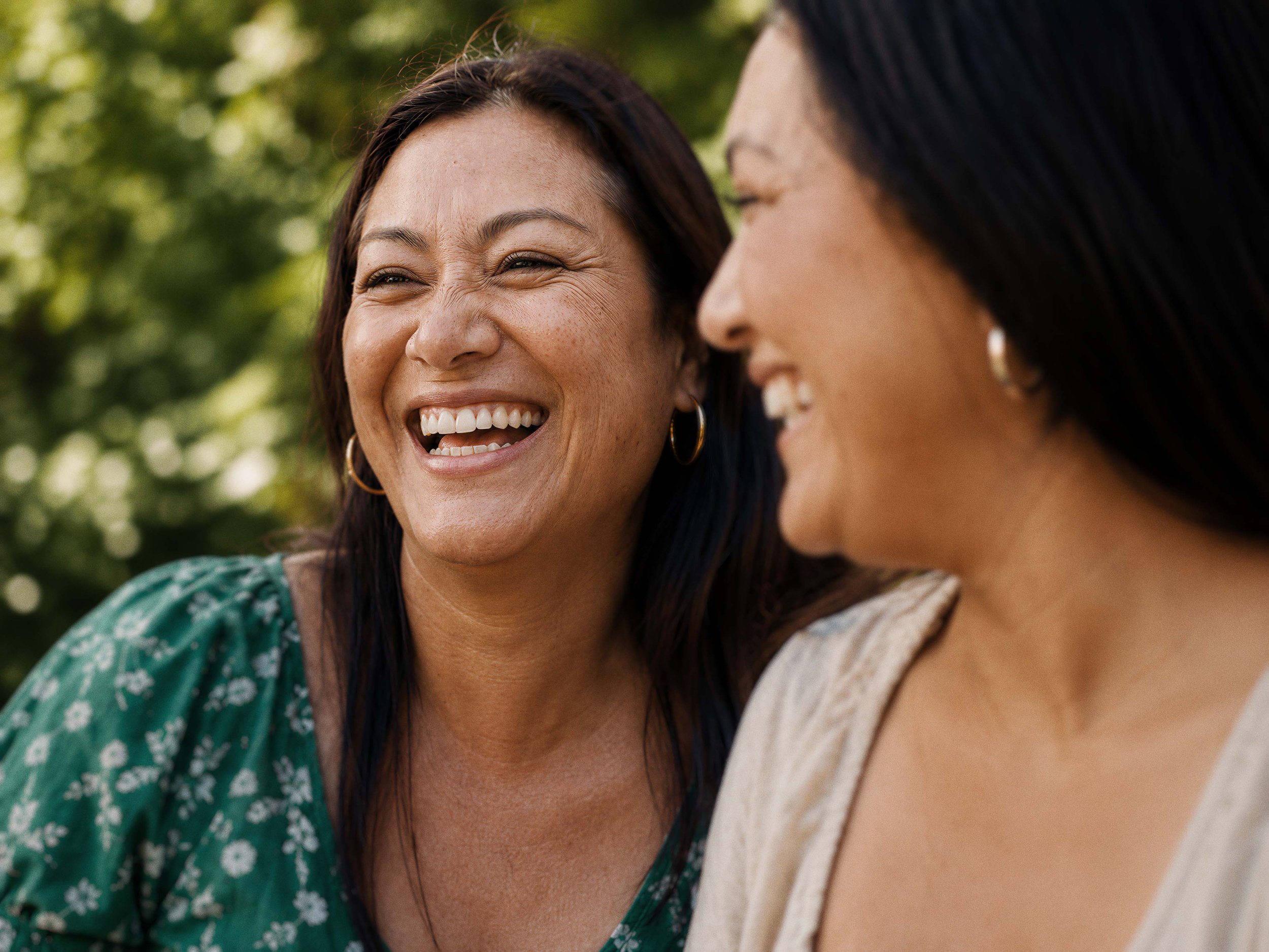 Two women smiling and laughing outdoors. Supportive women's health care in Wellington.
