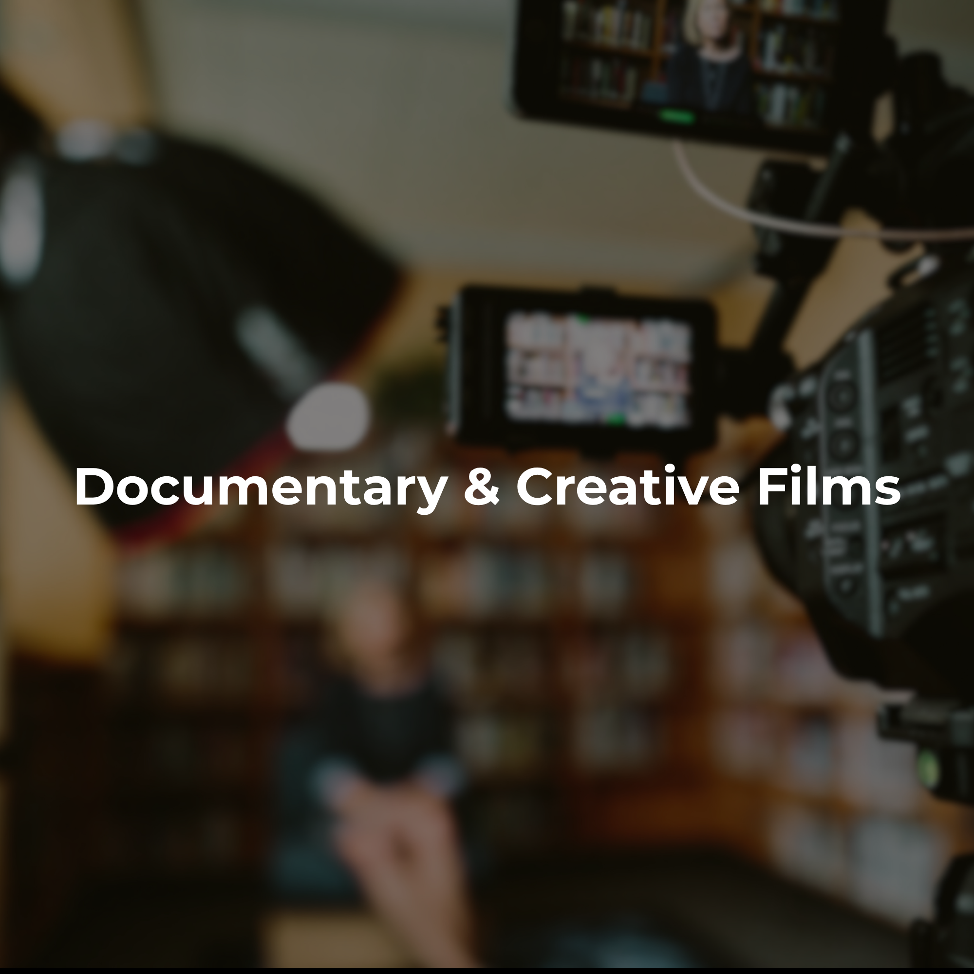 Documentary film production with a video camera recording inside a library or book-filled creative environment.
