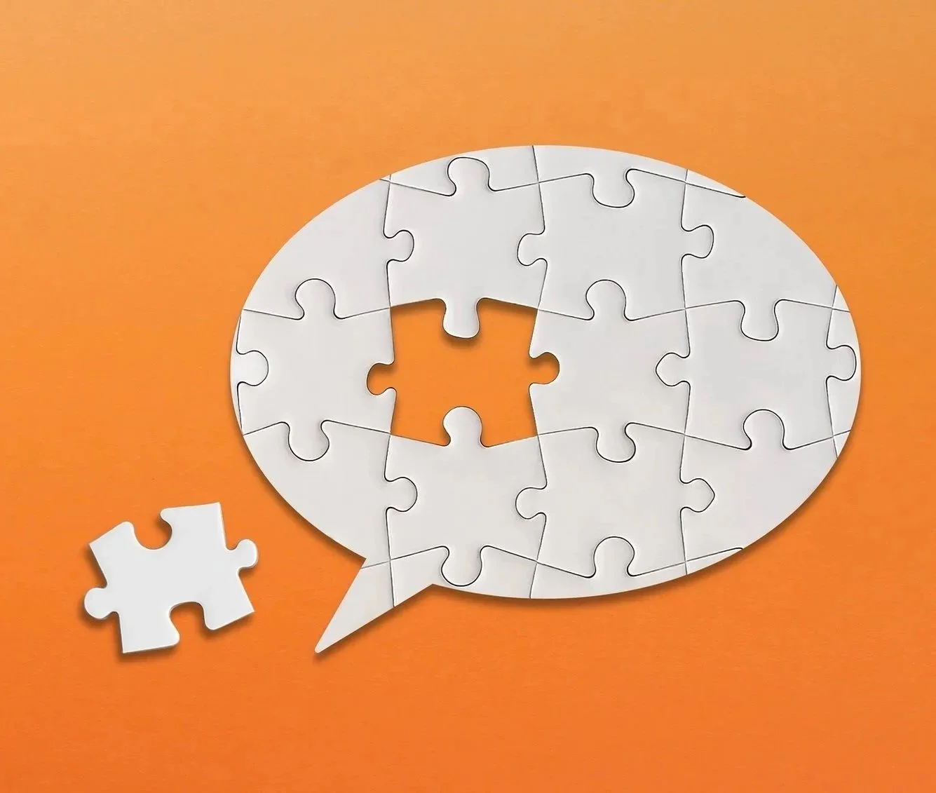 A puzzle in the shape of a speech bubble, with one piece missing, on an orange background.