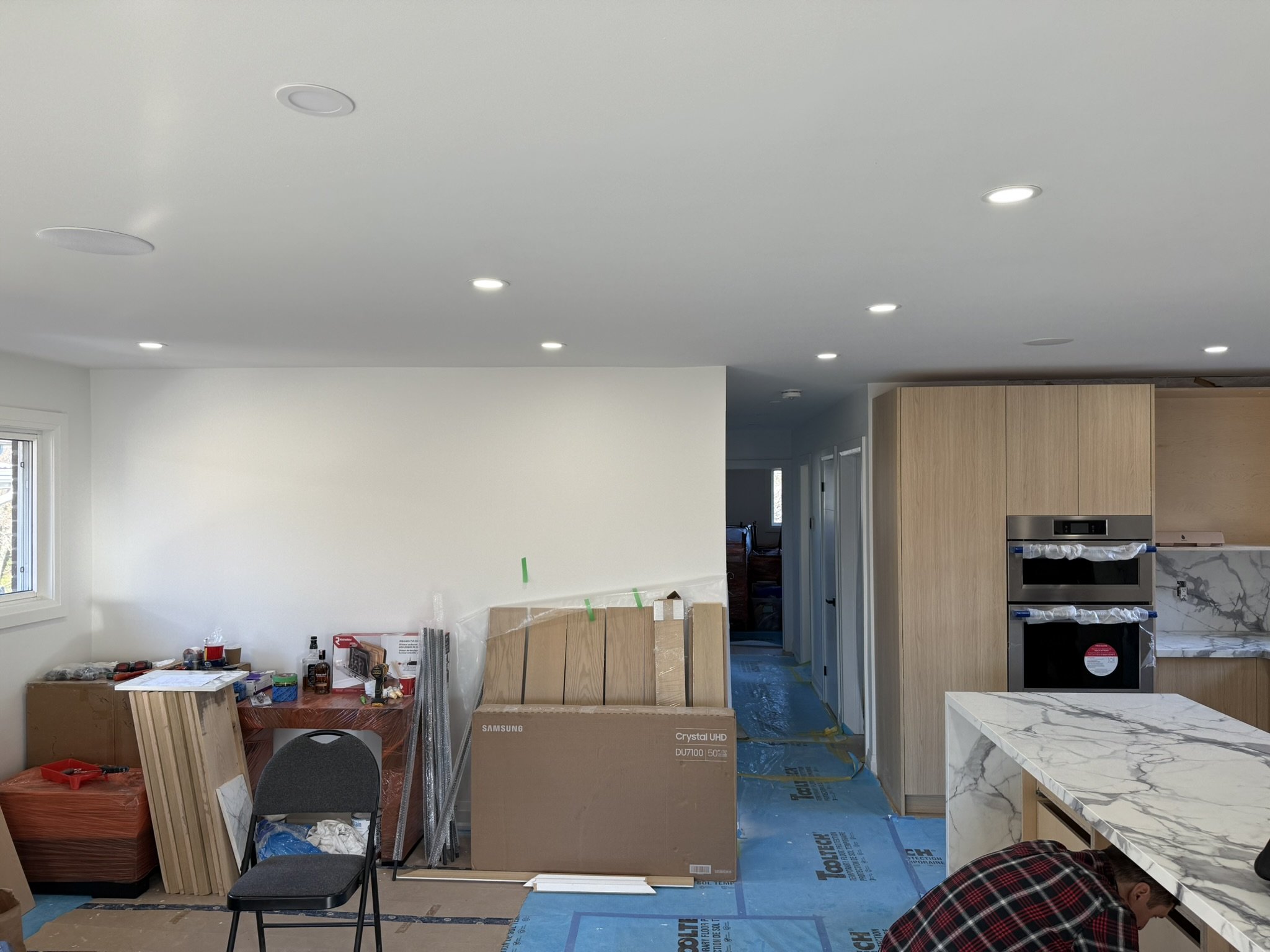 A room under construction or renovation with a partially finished kitchen, with pot lights overcut repaired.