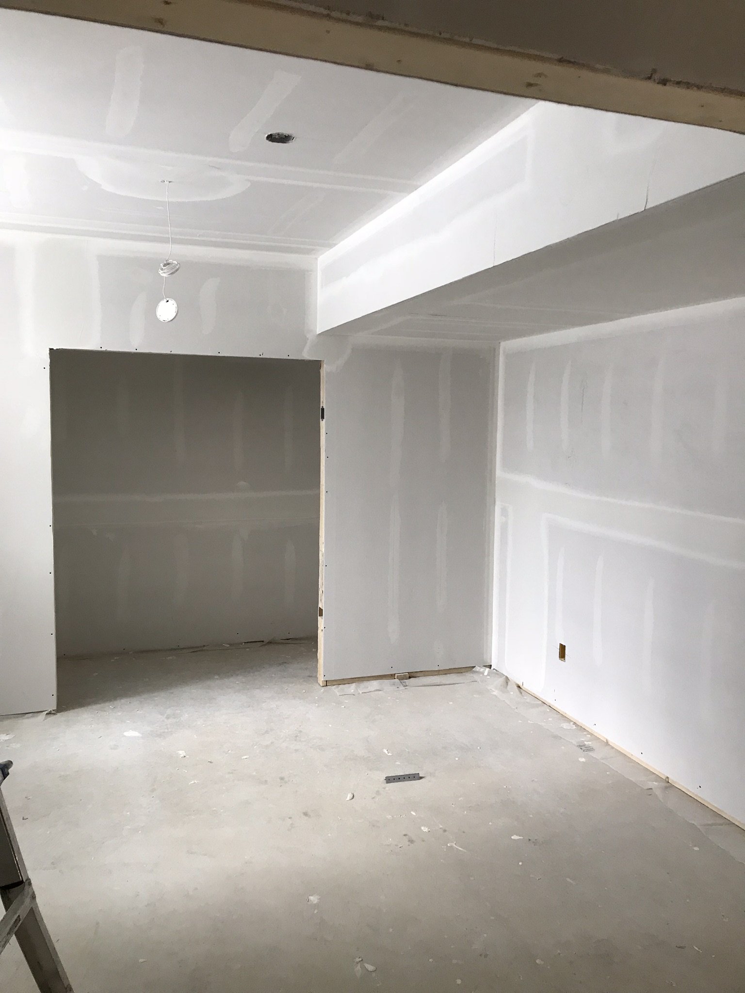 A room under construction with drywall installed on the walls and ceiling. In Mississauga, there is a doorway without a door and an electrical outlet visible on the wall.