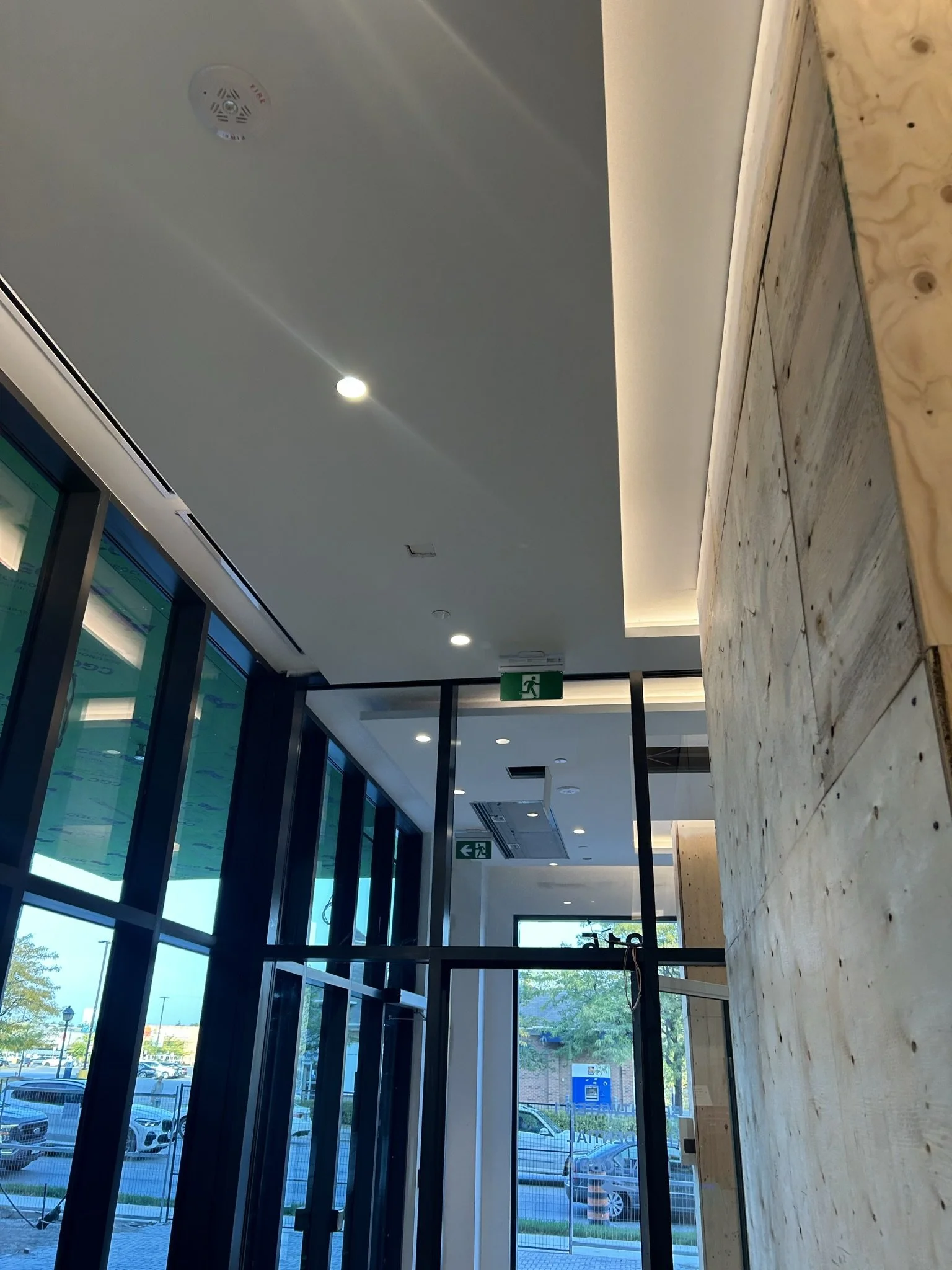 Interior view of a modern building with large glass windows, ceiling lights, and a wooden wall in Mississauga.