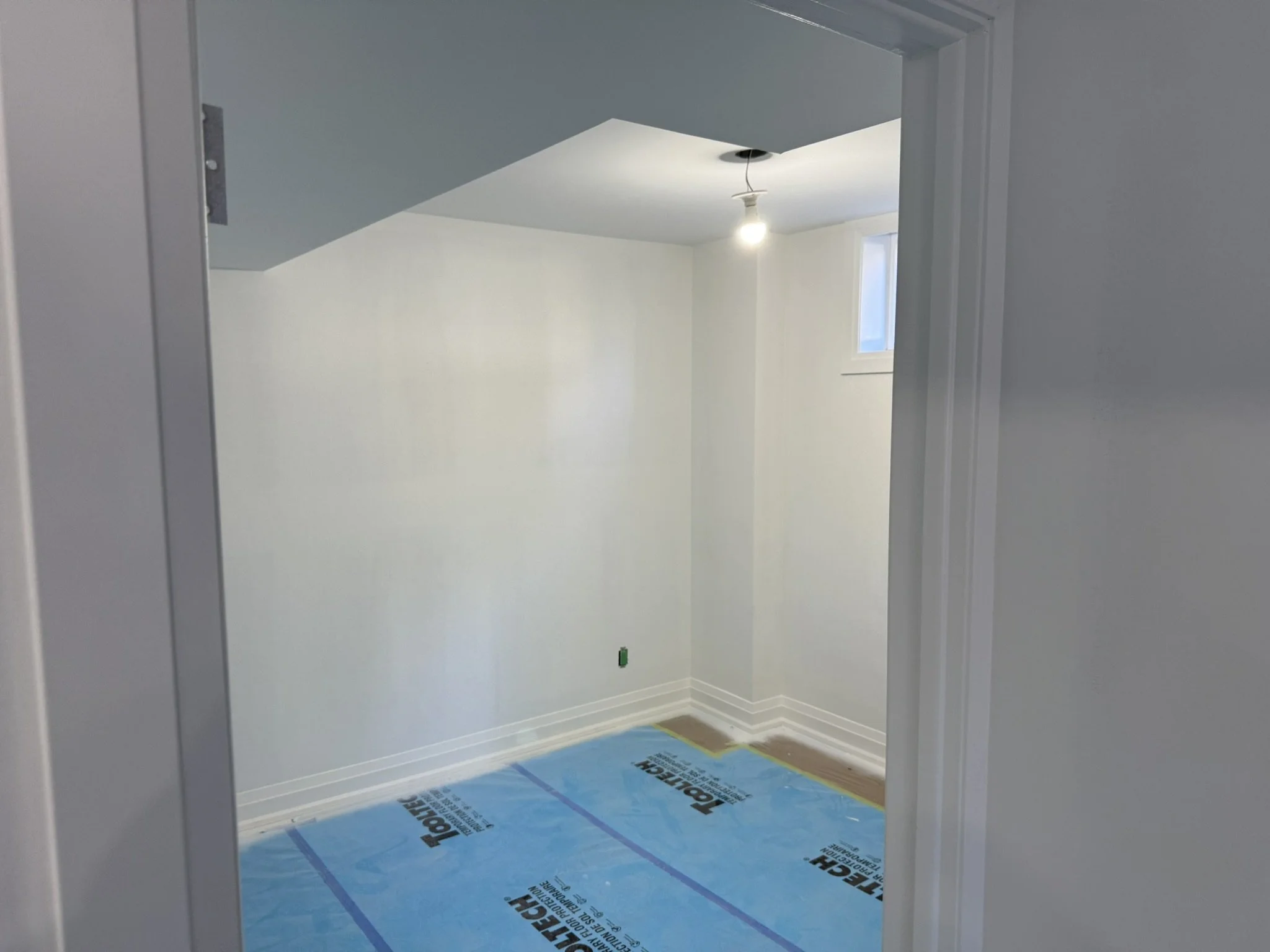 View of a basement bedroom under construction, with new drywall and plaster.