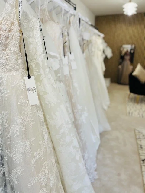 Wedding dresses hanging on a rack in a bridal boutique.