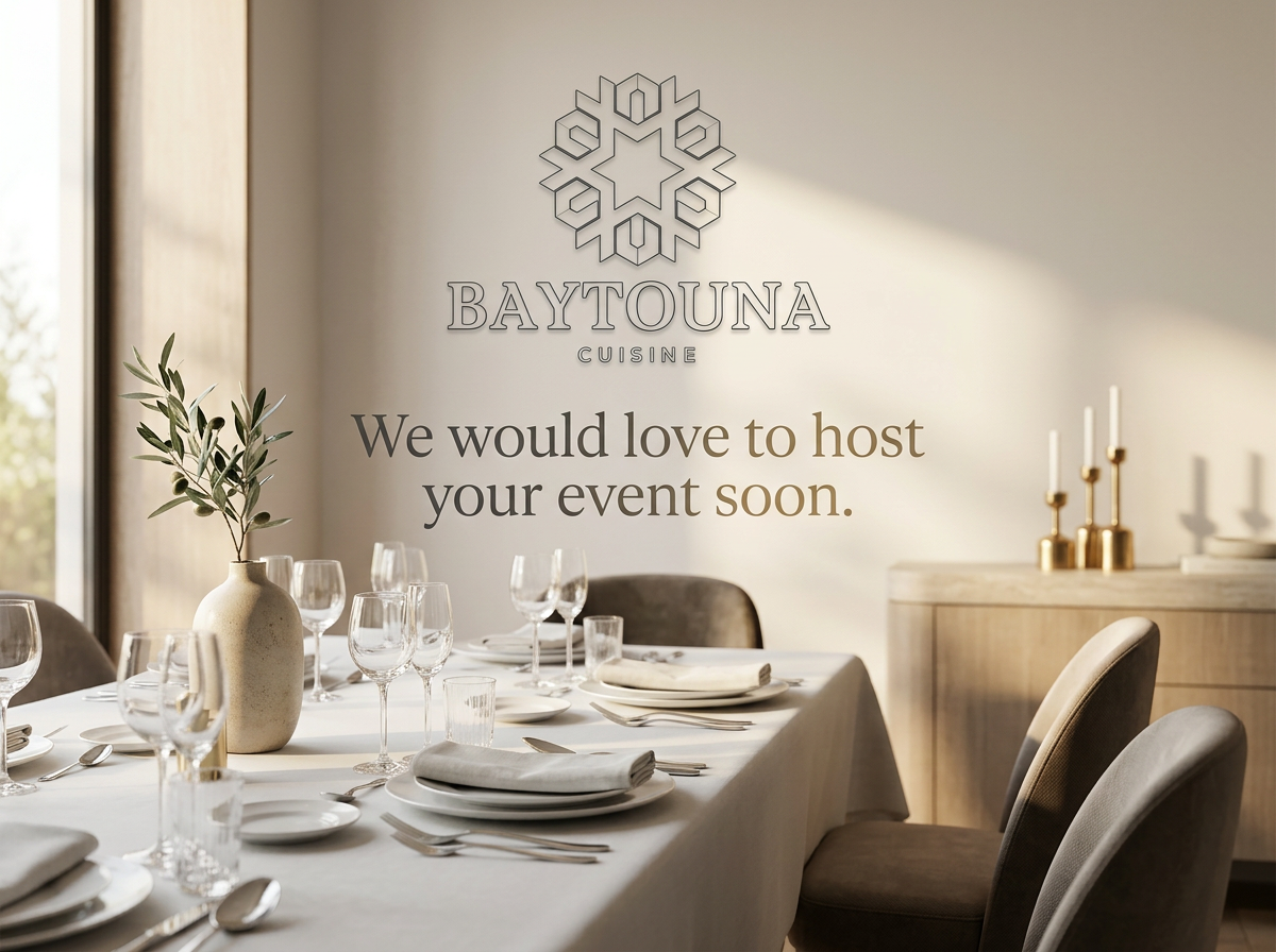 Elegant dining setup with a white tablecloth, glassware, plates, utensils, and a vase with greenery. The wall features the logo and name 'Baytouna Cuisine,' with a message inviting to host events.
