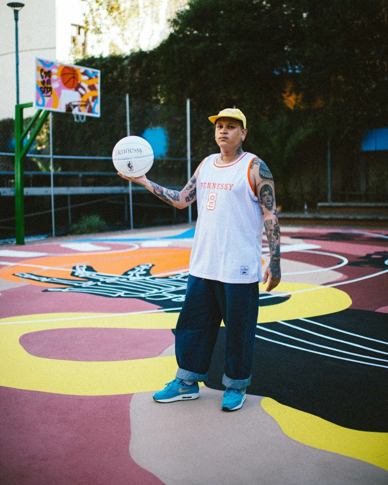 African Ginger aka Seth Pimentel on the colourful outdoor basketball court that he designed in Braamfontein, Johannesburg. Made in collaboration with Play Braamfontein, NBA Africa and Hennessy.