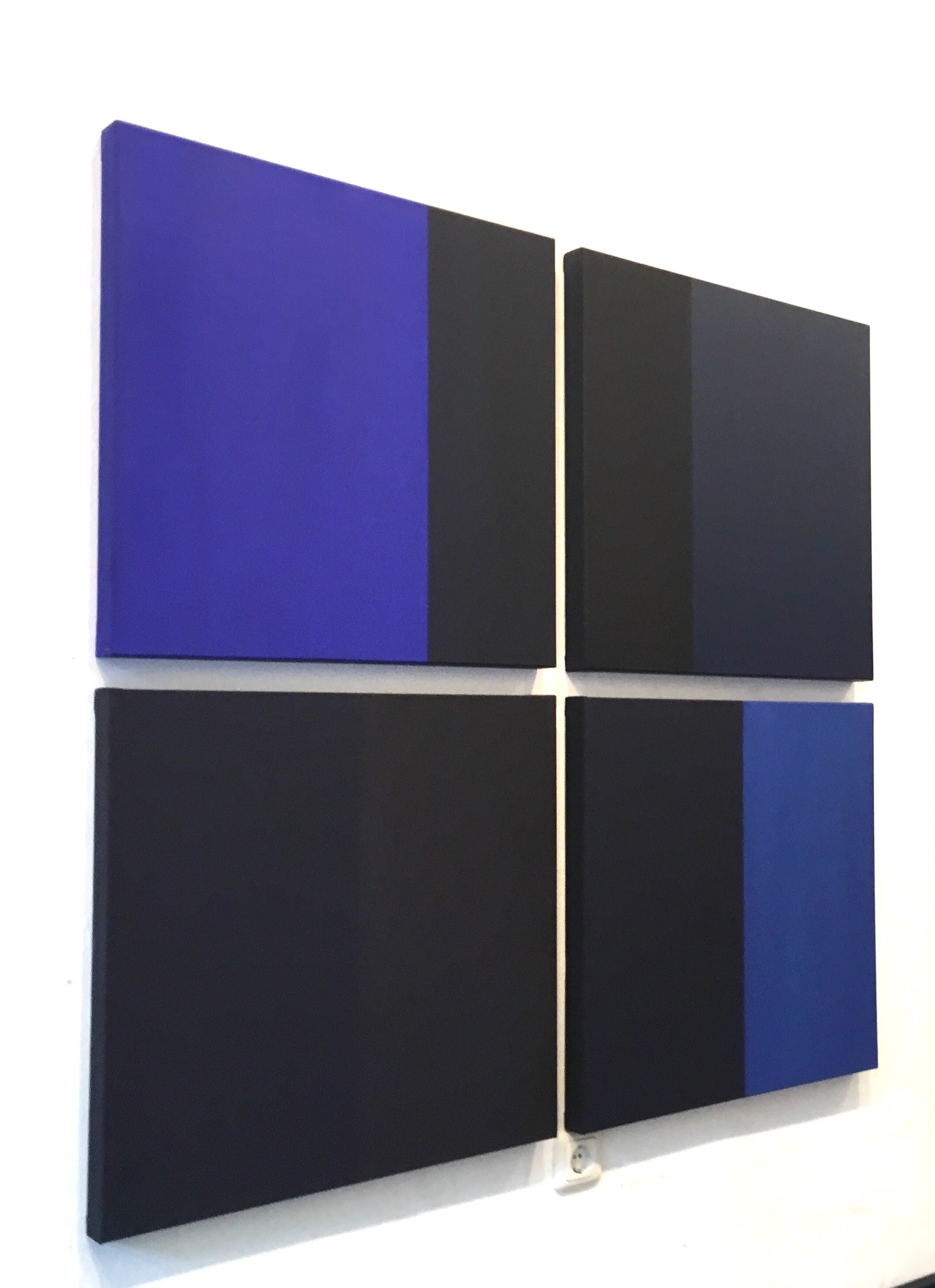 Two black and blue rectangular panels mounted on a white wall, with the larger blue panel on the left and the smaller black panel on the right.