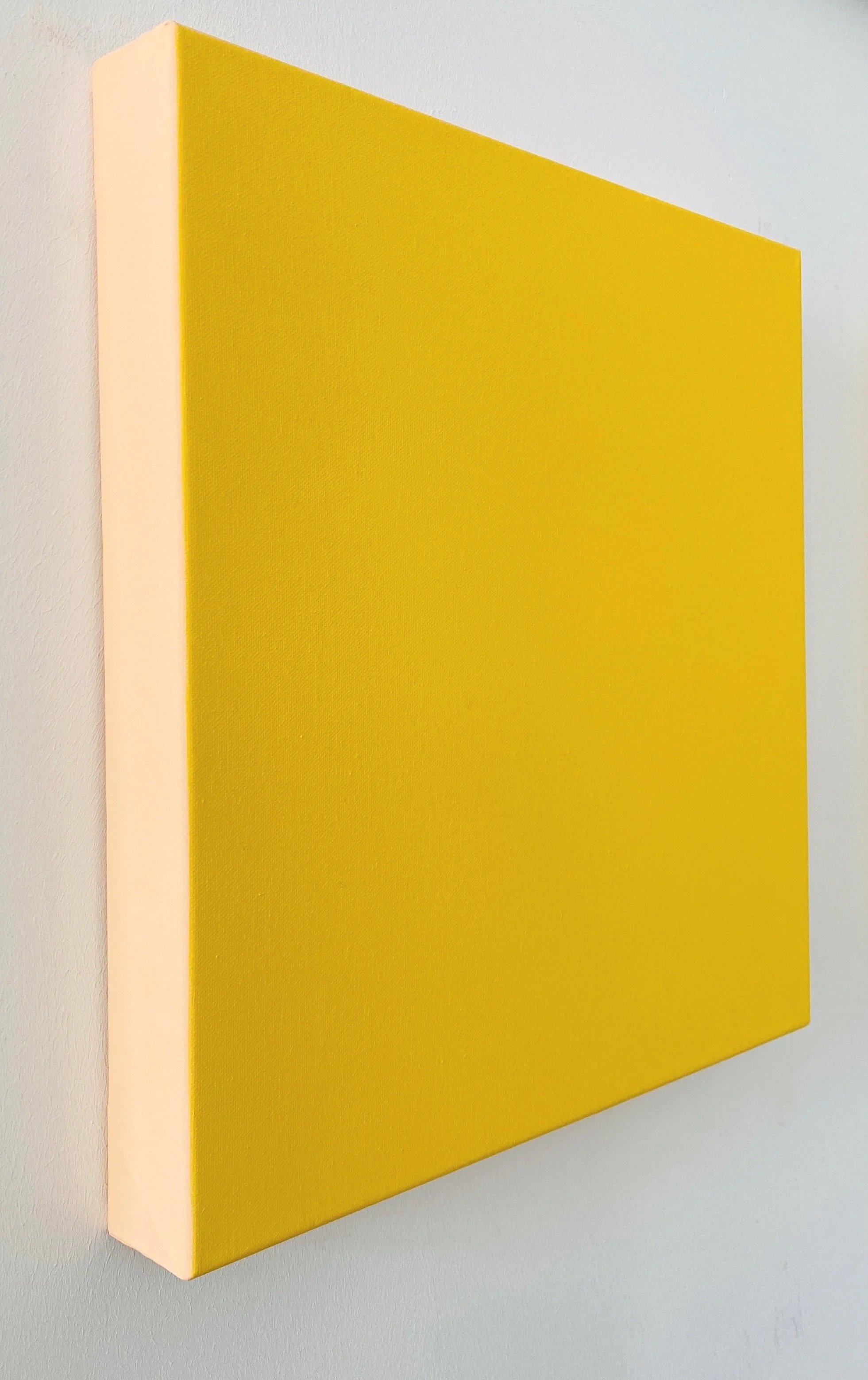 A rectangular yellow wall-mounted panel with a white border on the left side, against a white wall.