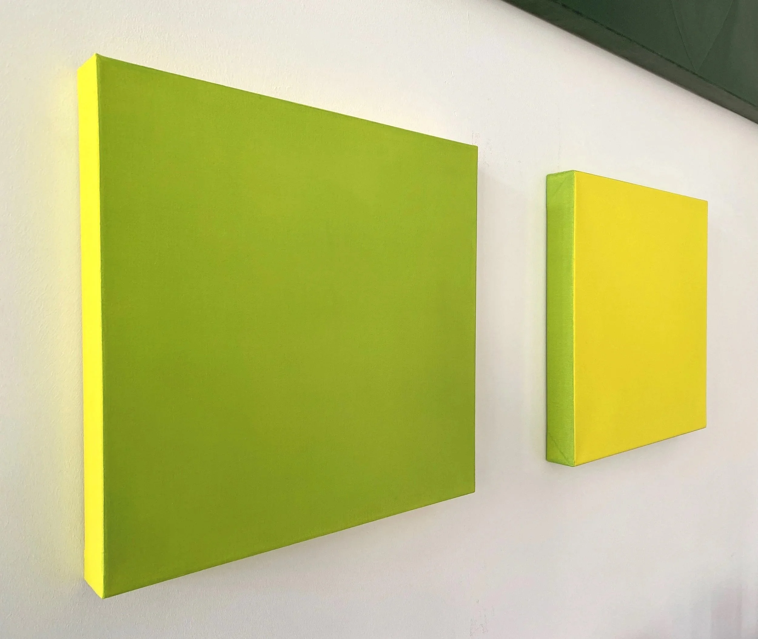 Close-up of a green and yellow wall-mounted panel or artwork with a geometric design, featuring overlapping rectangular shapes.