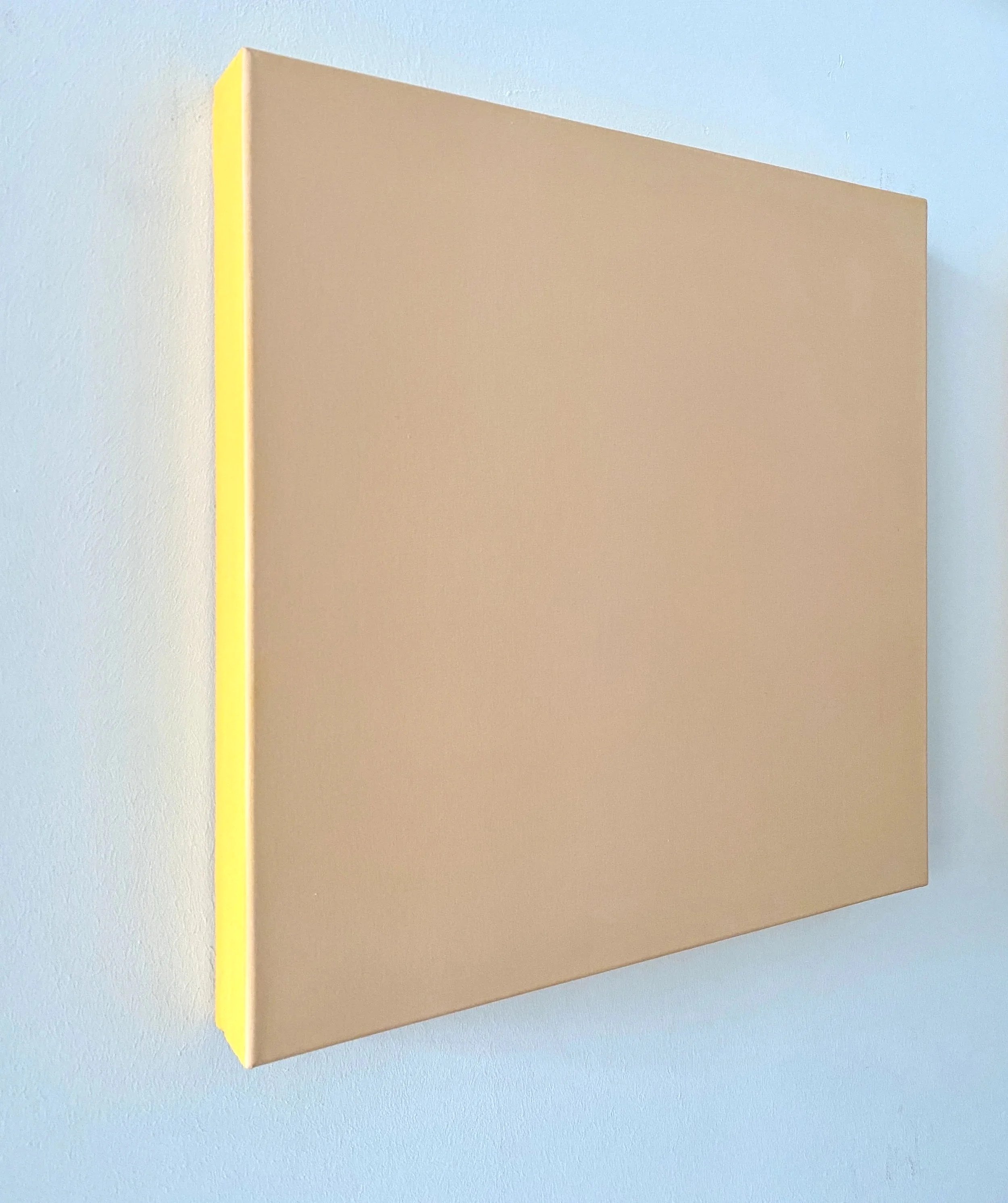 A beige-colored book or notebook with a yellow spine placed on a light blue surface.