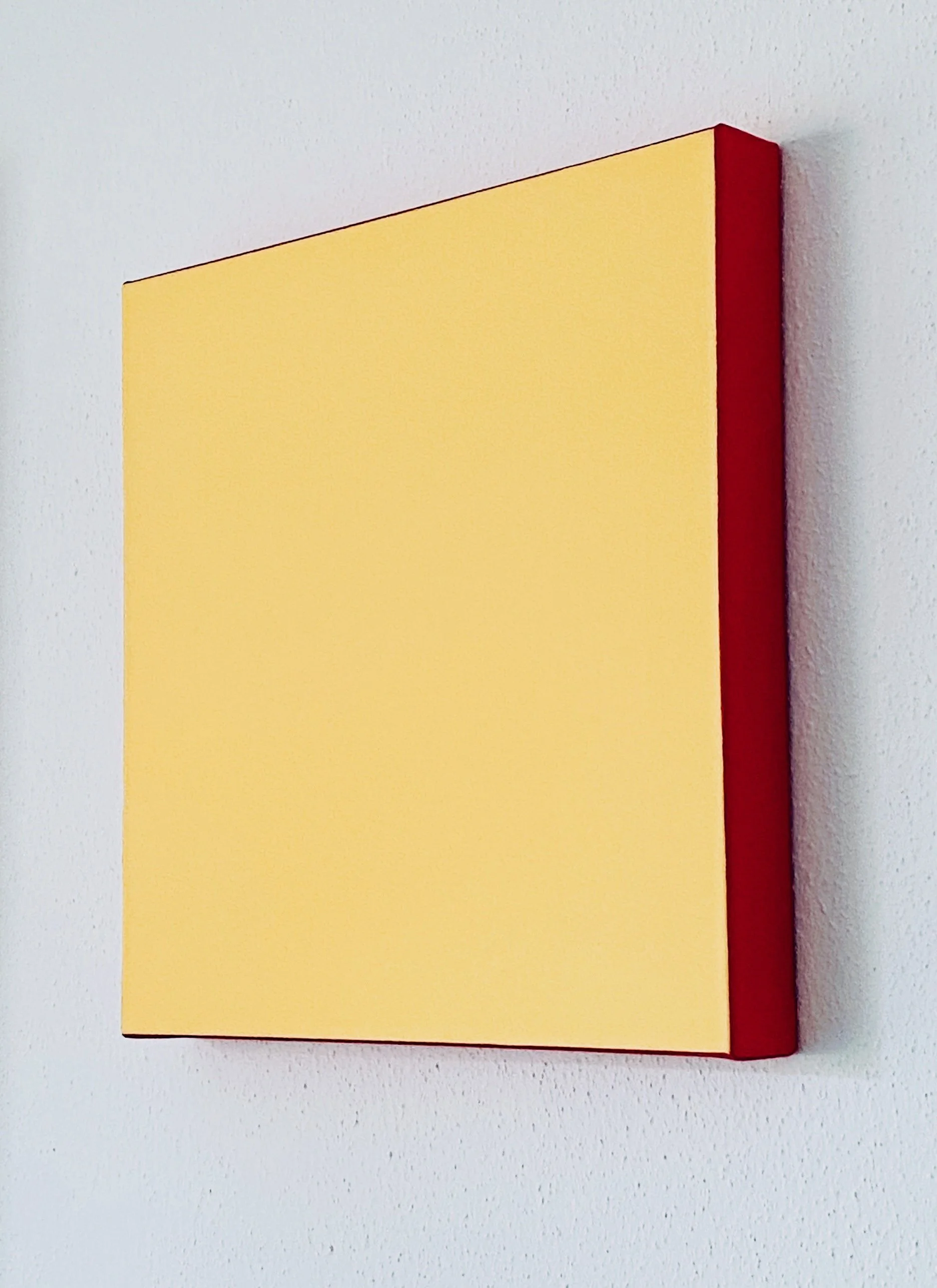 Yellow book with a red spine standing upright on a white surface.