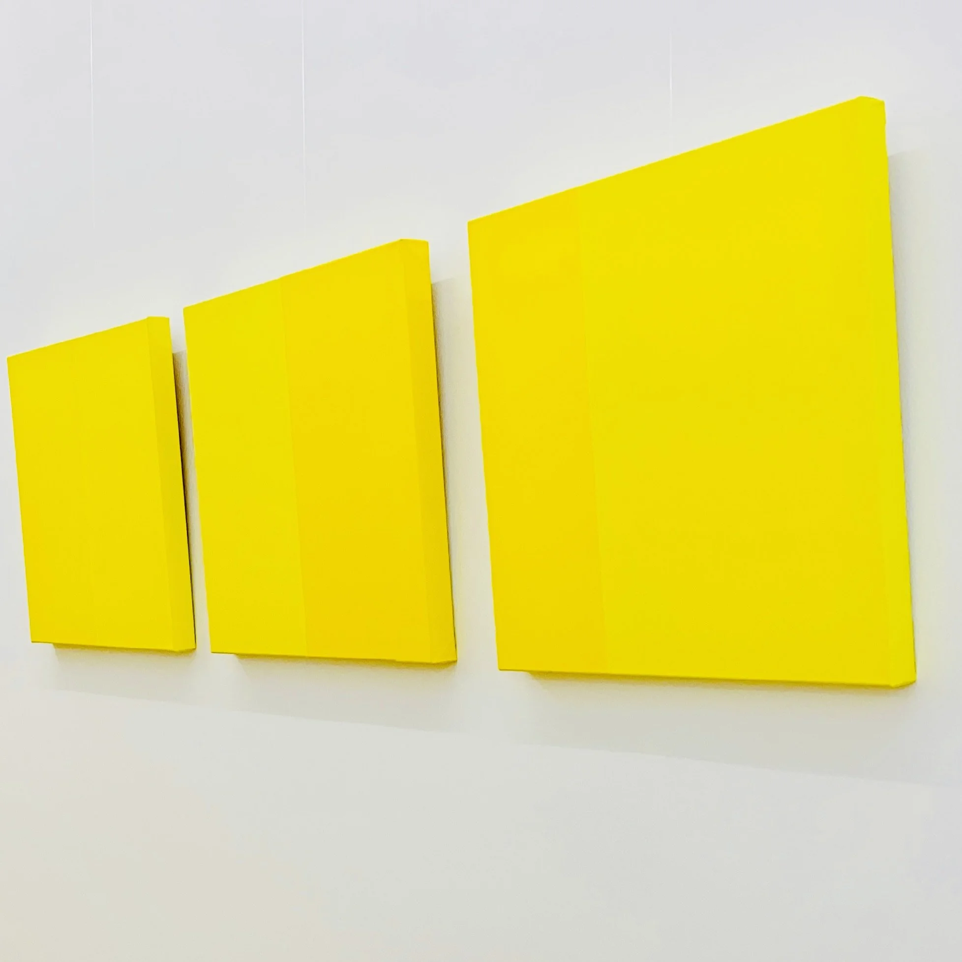 Close-up image of four vertical yellow plastic or wooden slats with varying heights, mounted on a white background.