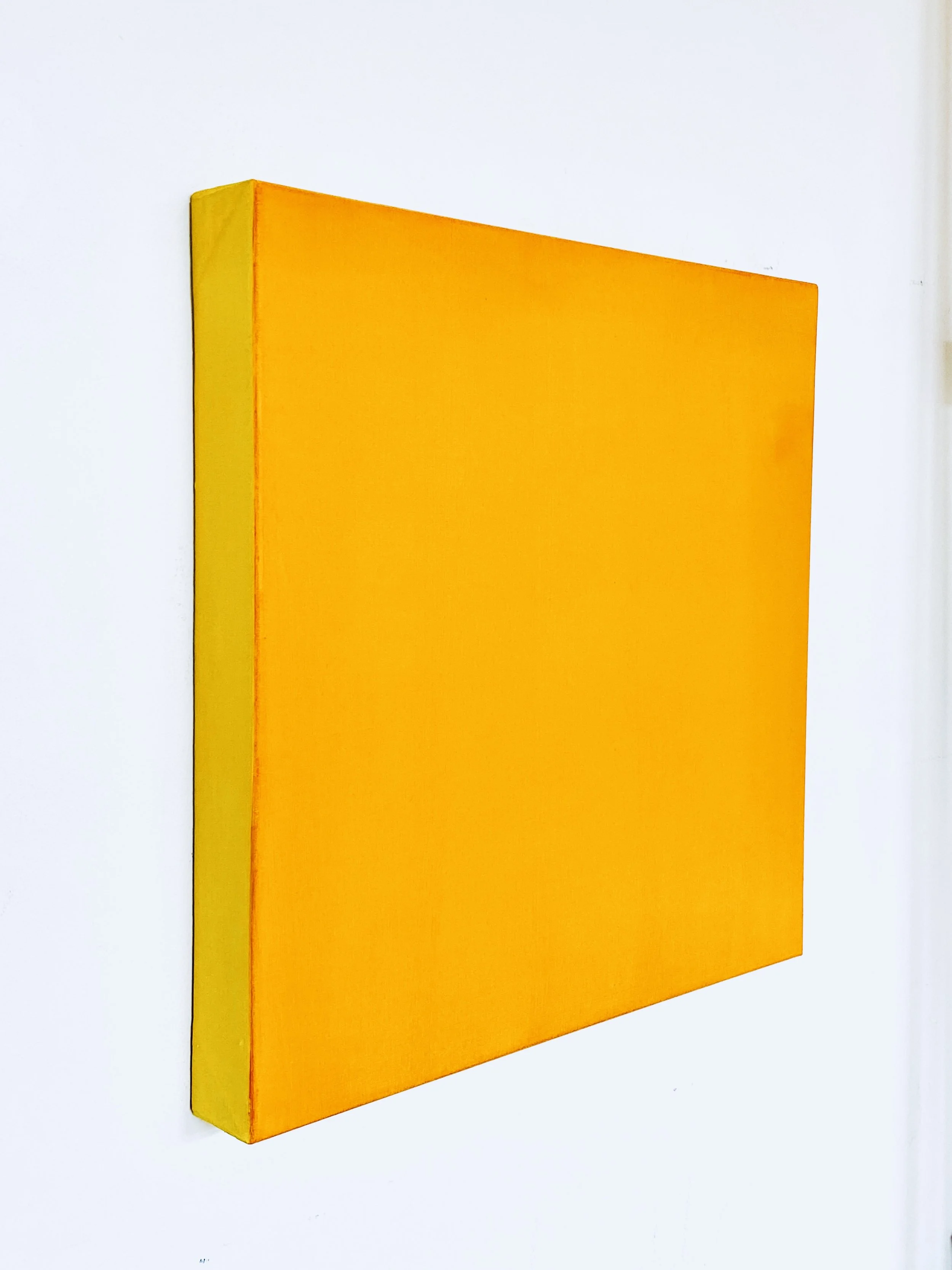 A rectangular orange and yellow wall art piece mounted on a white wall.