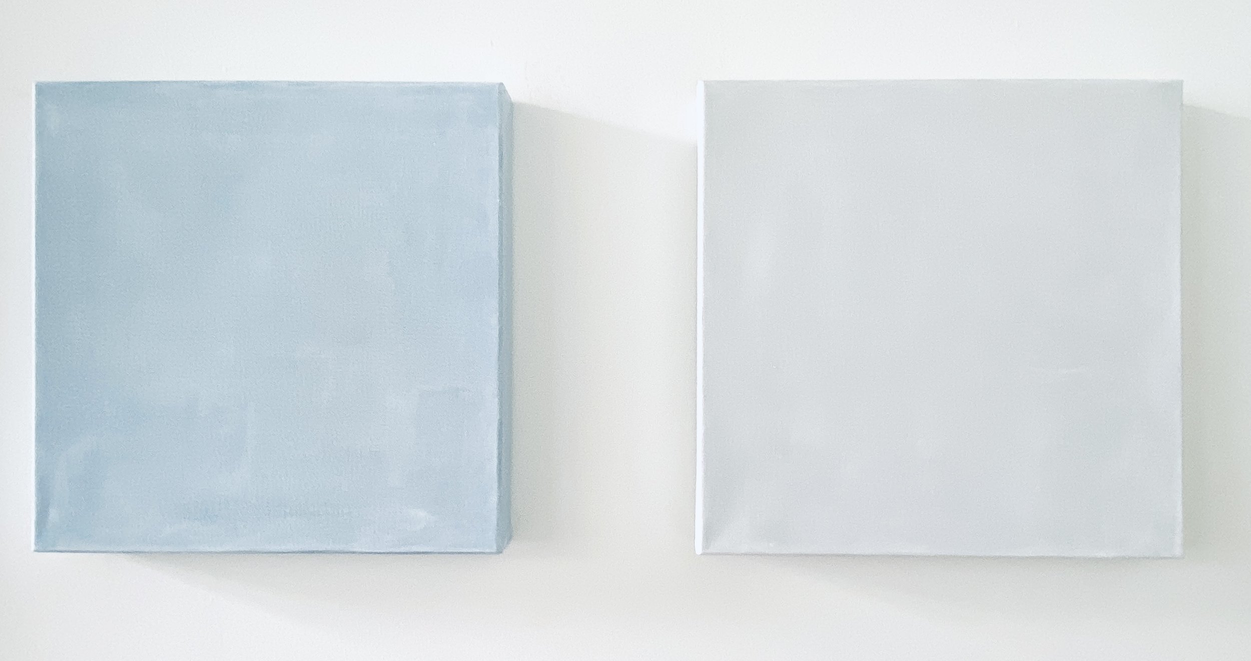 Two rectangular objects, one light blue and one white, are placed side by side on a white surface.