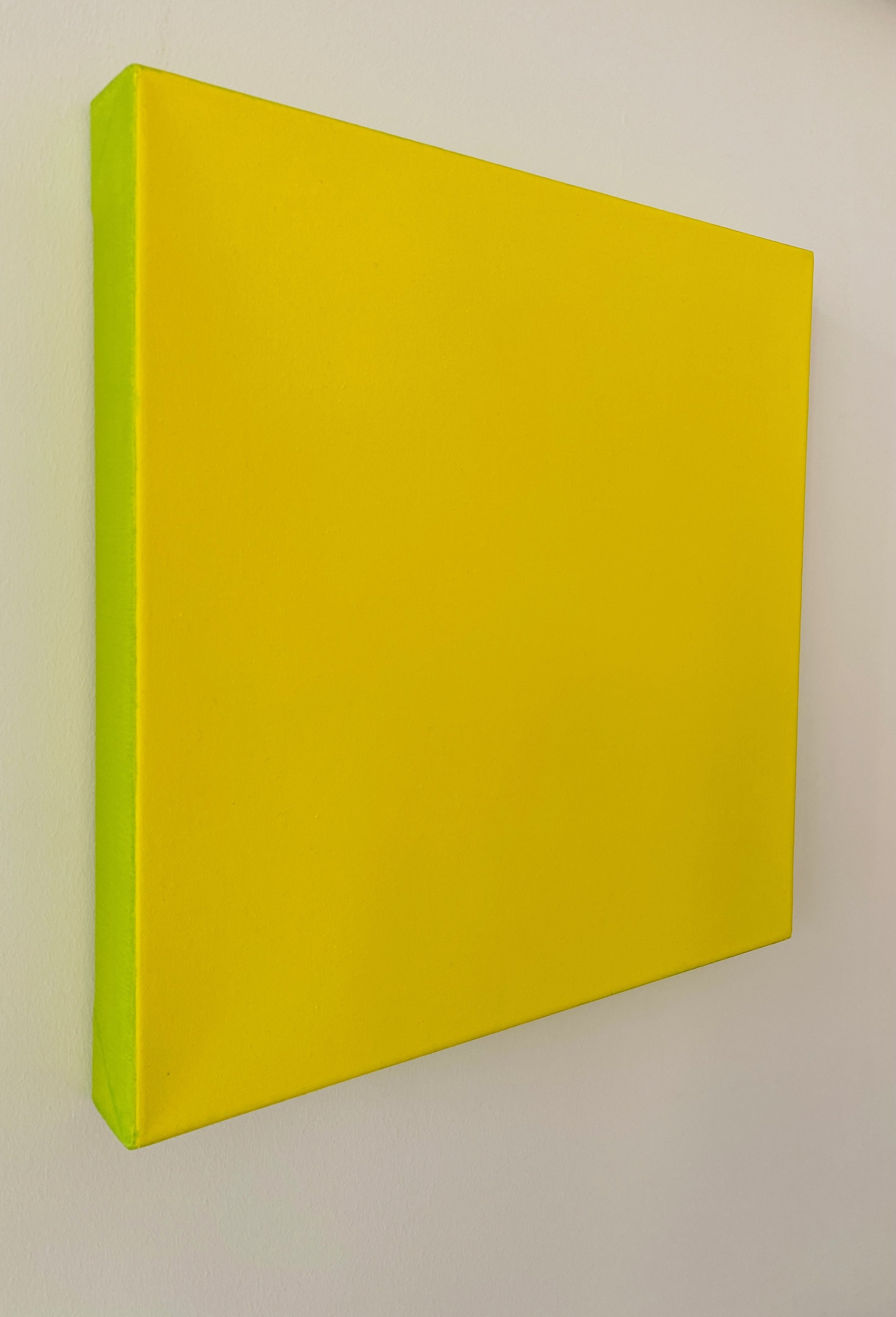 Colorful modern art panel with yellow and green sections, mounted on a white wall.