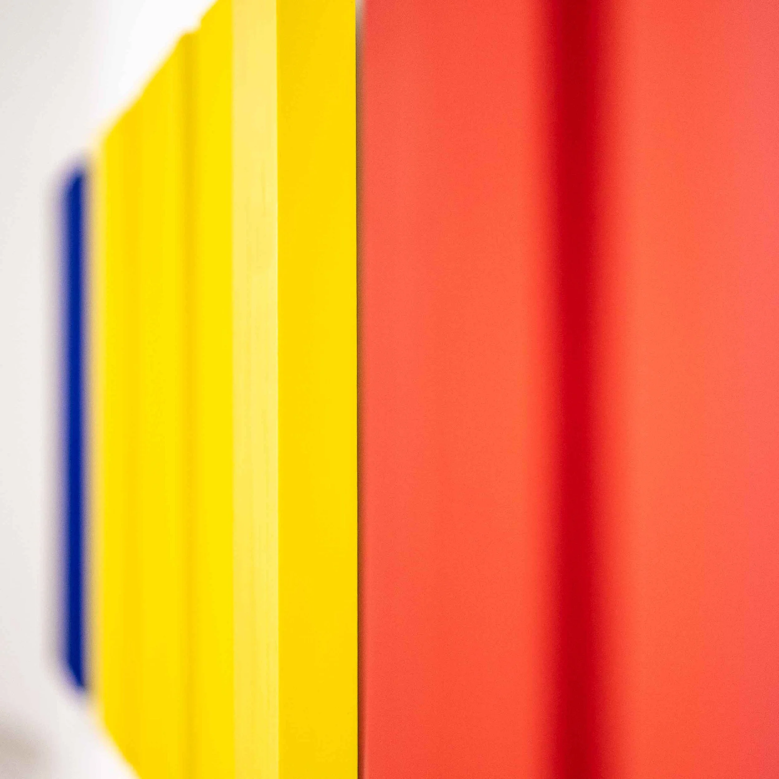Close-up of a colorful abstract pattern with bold vertical stripes in white, yellow, blue, and red.