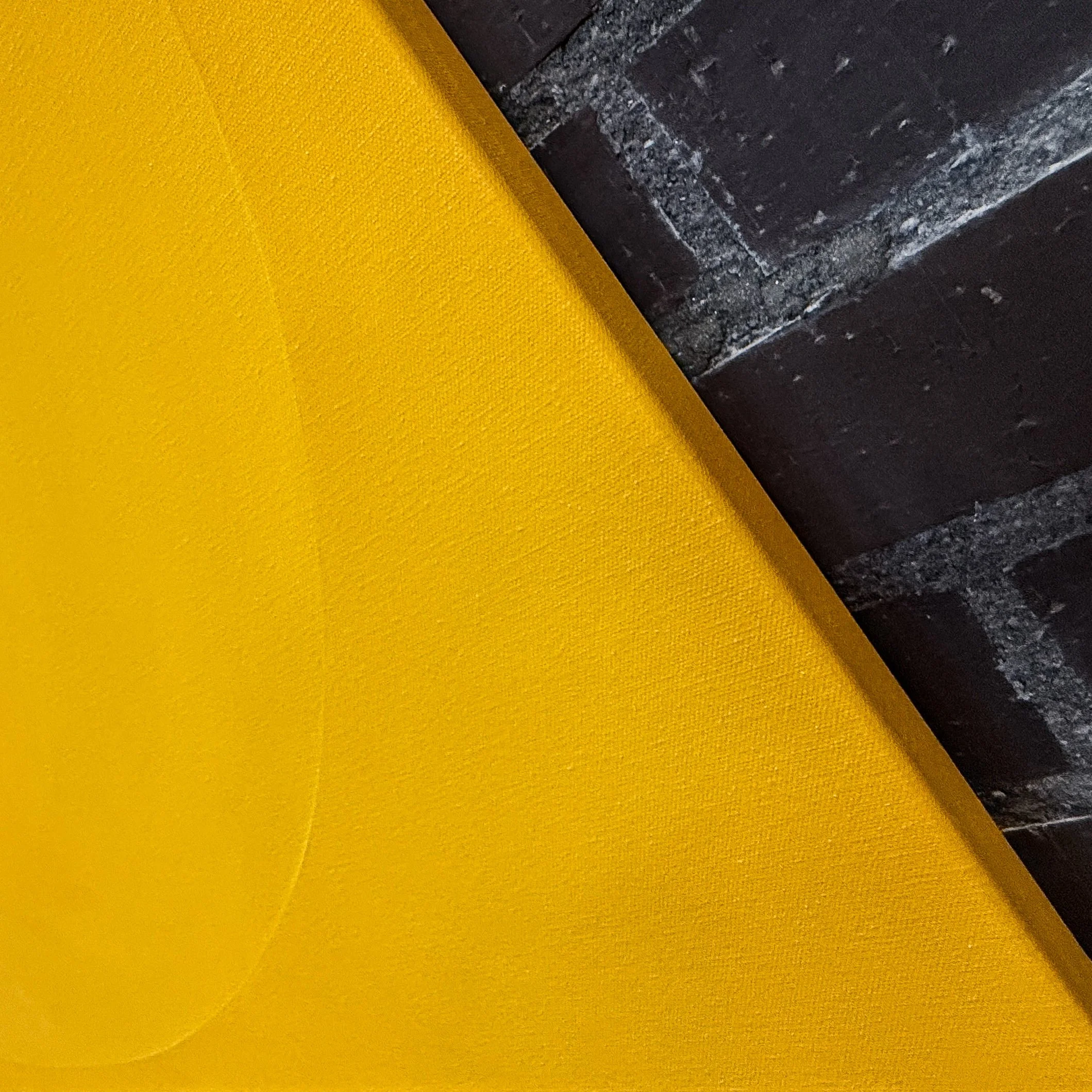 Close-up of a yellow fabric surface, with black textured stone or concrete along the right edge.