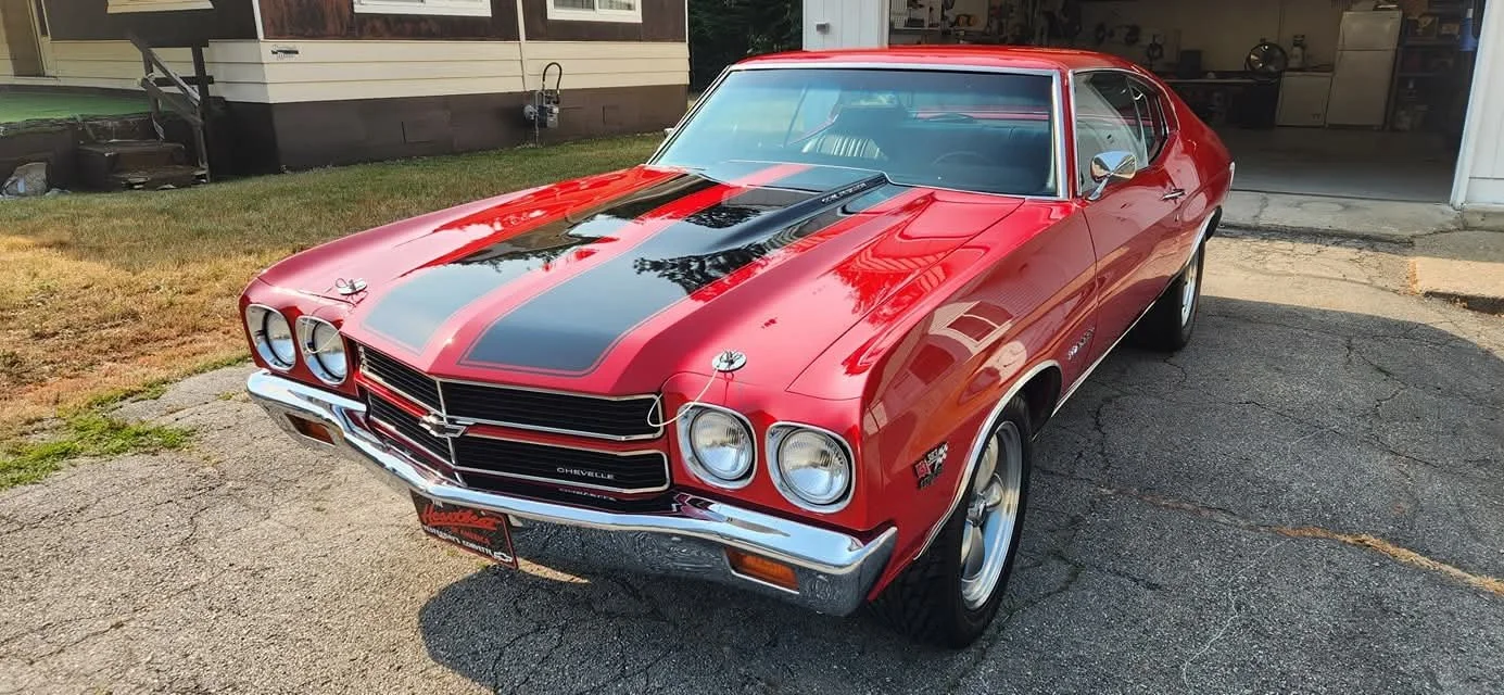 Red vintage Chevrolet Chevelle with black racing stripe having just been polished and freshly coated.