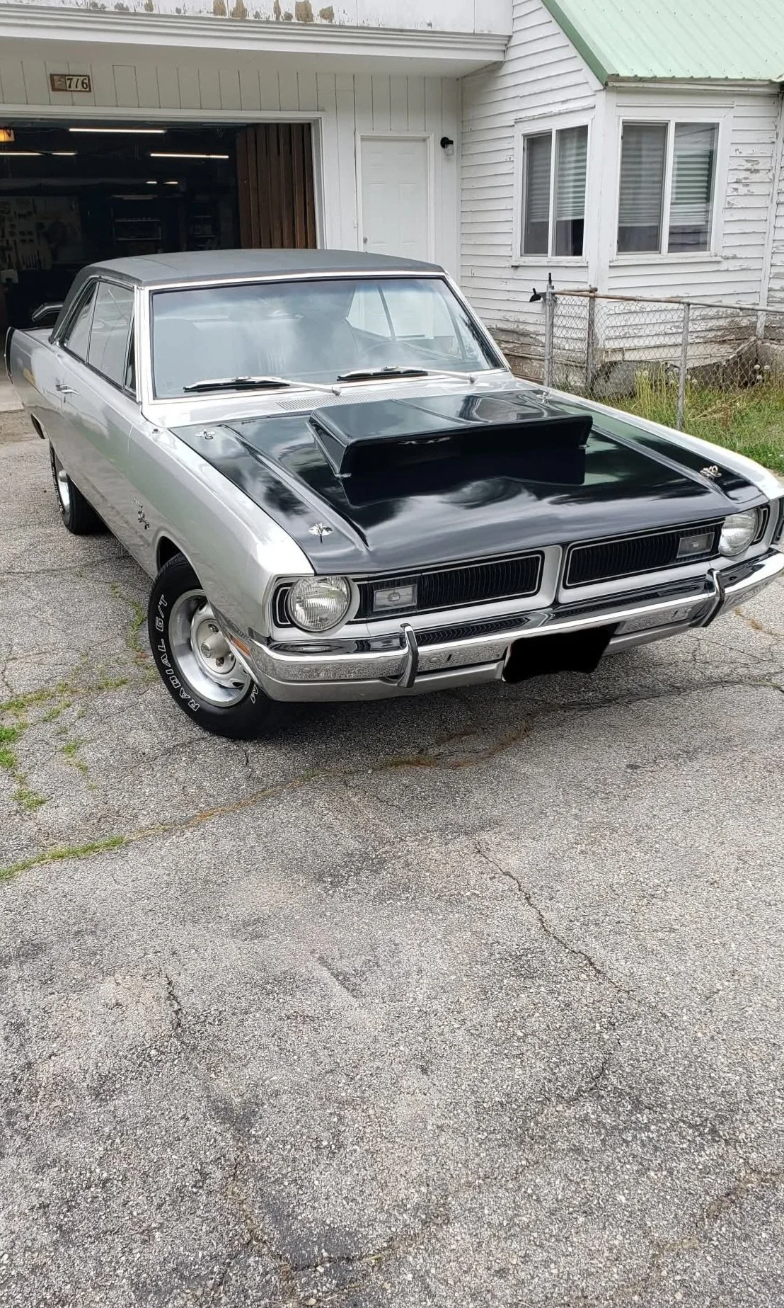 A classic silver and black muscle car with a hood scoop, having just had an exterior detail on it