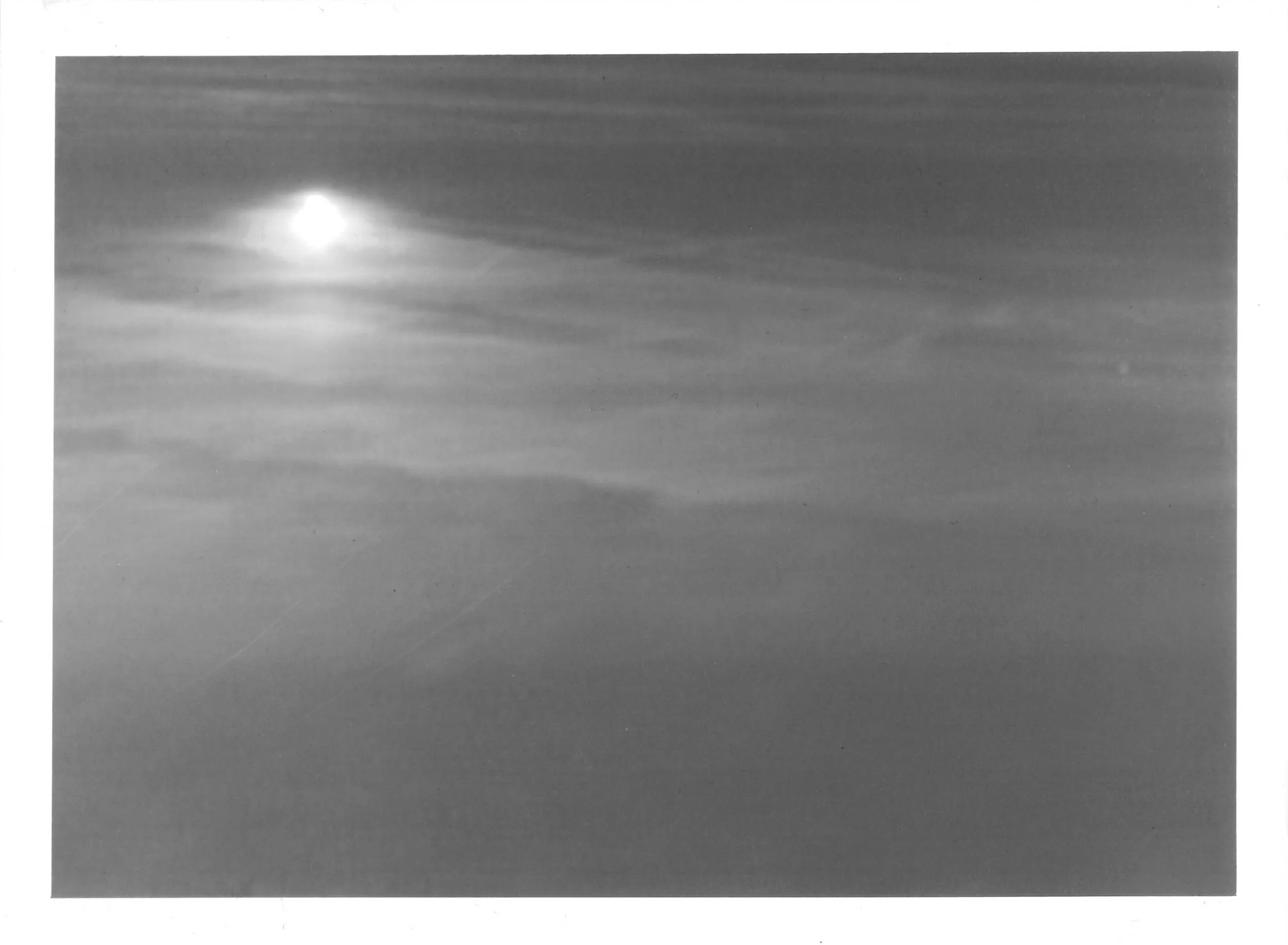 Fotografia analógica em preto e branco, integrante da Série 3, de Sandra Unglert Fernandes, apresentando um foco de luz sobre uma superfície, com suaves gradações tonais que lembram uma aquarela.