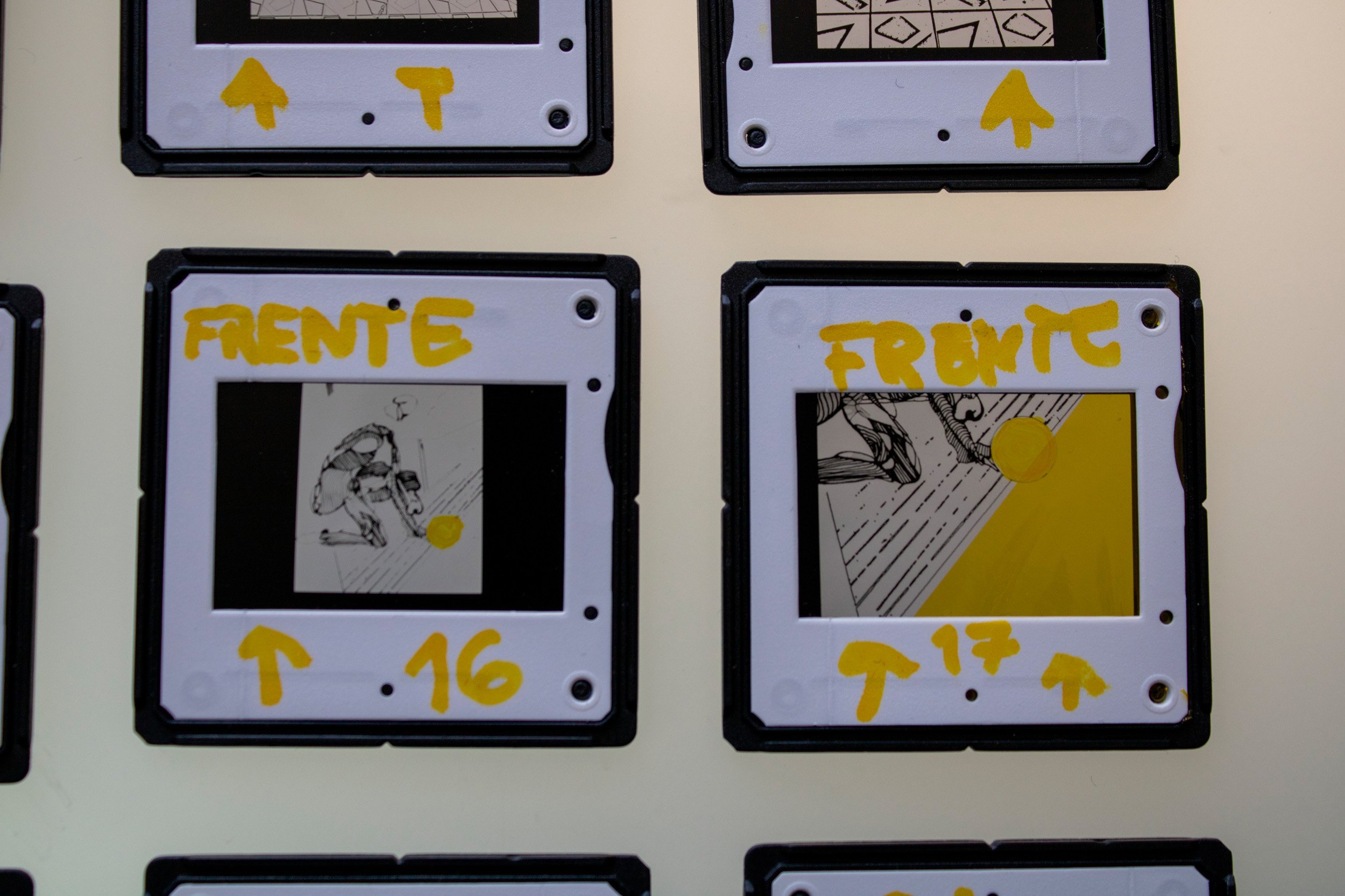 Dois slides fotográficos analógicos em preto e branco da série Slides – Fotografia, de Sandra Unglert Fernandes, mostrando desenhos e intervenção em papel celofane amarelo.