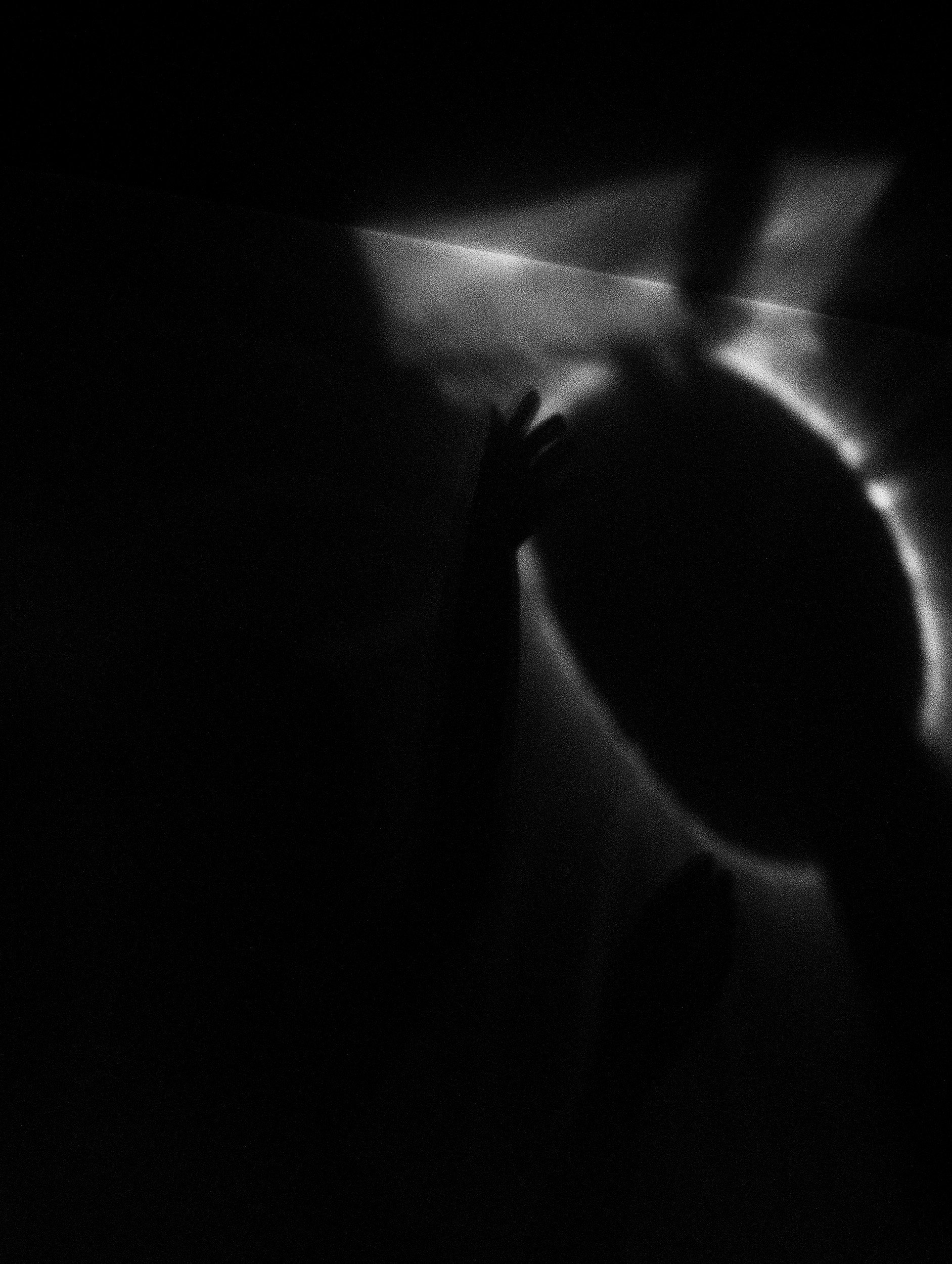 Fotografia digital em preto e branco, integrante da Série Digital 2, de Sandra Unglert Fernandes, mostrando a silhueta de uma figura humana diante de halos e reflexos luminosos.