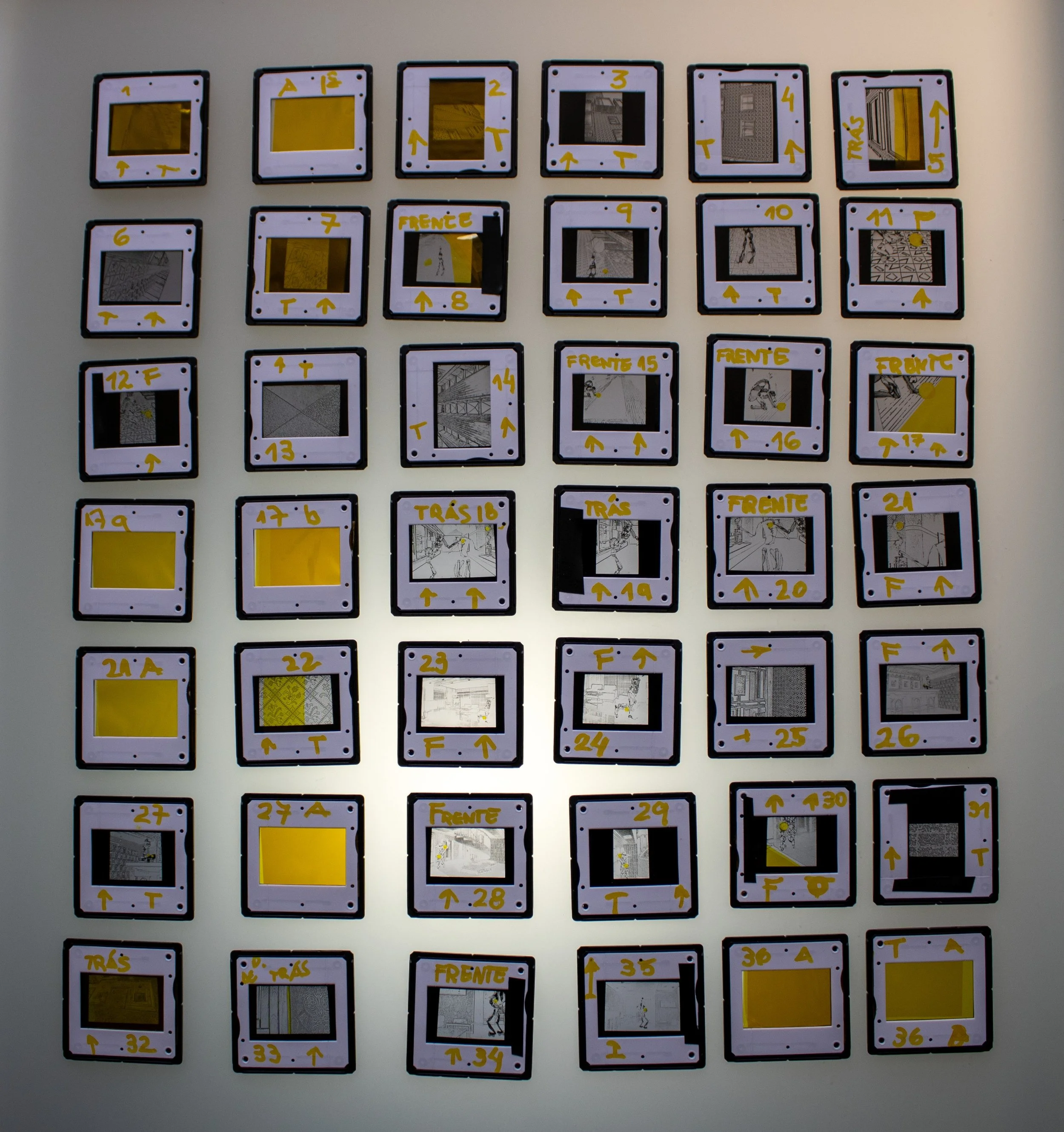 Conjunto de slides fotográficos analógicos organizados em grade, integrante da série Slides – Fotografia, de Sandra Unglert Fernandes, com anotações manuscritas e marcações em amarelo.