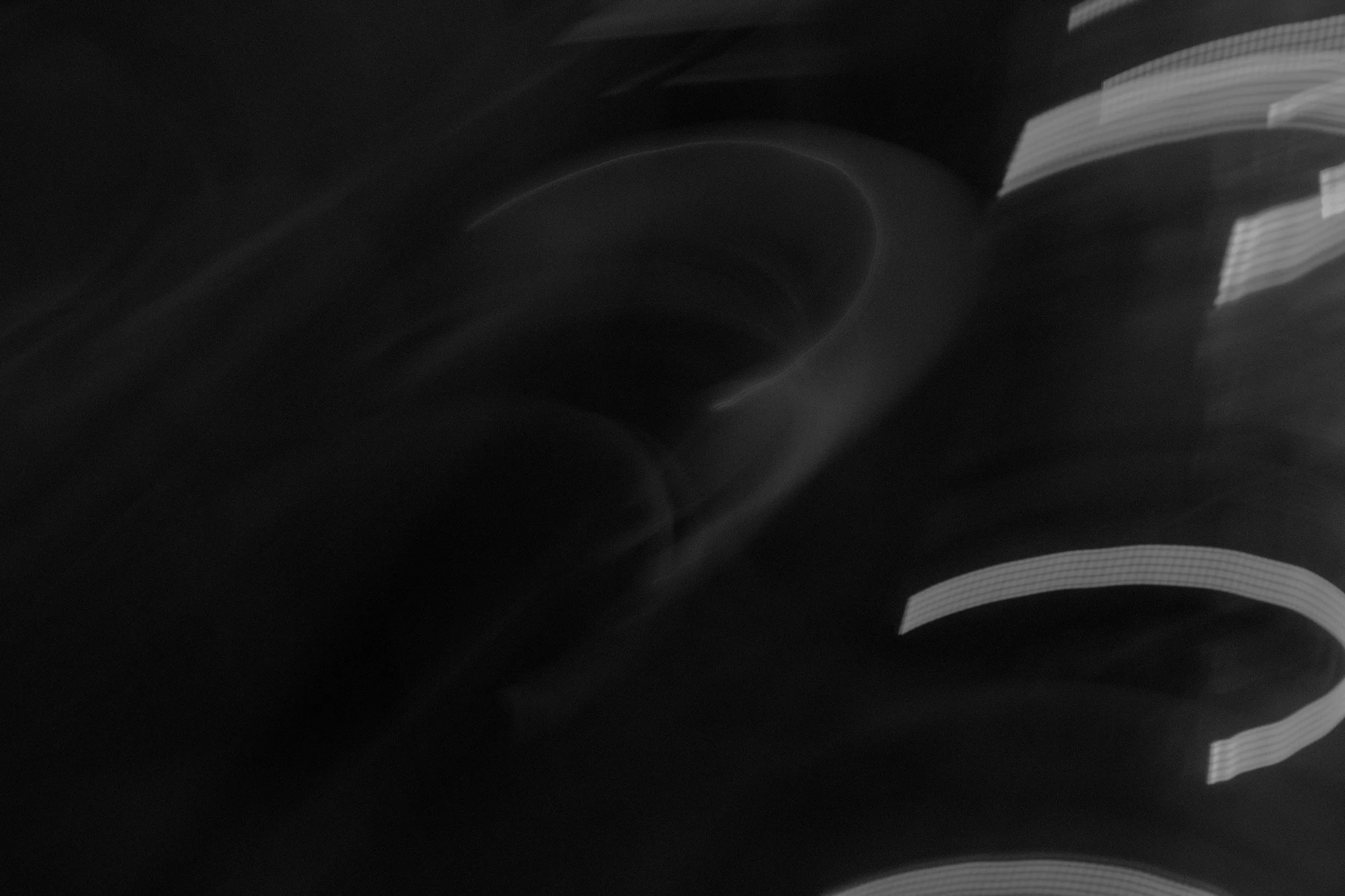 Fotografia digital em preto e branco, integrante da Série Digital 1, de Sandra Unglert Fernandes, mostrando formas abstratas em movimento, com traços luminosos e áreas desfocadas.
