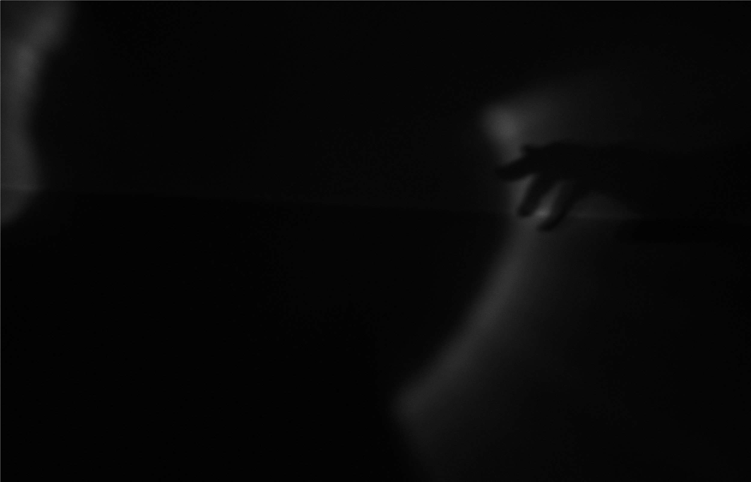 Fotografia digital em preto e branco, integrante da Série Digital 2, de Sandra Unglert Fernandes, mostrando uma mão parcialmente iluminada e halos de luz em uma composição abstrata.