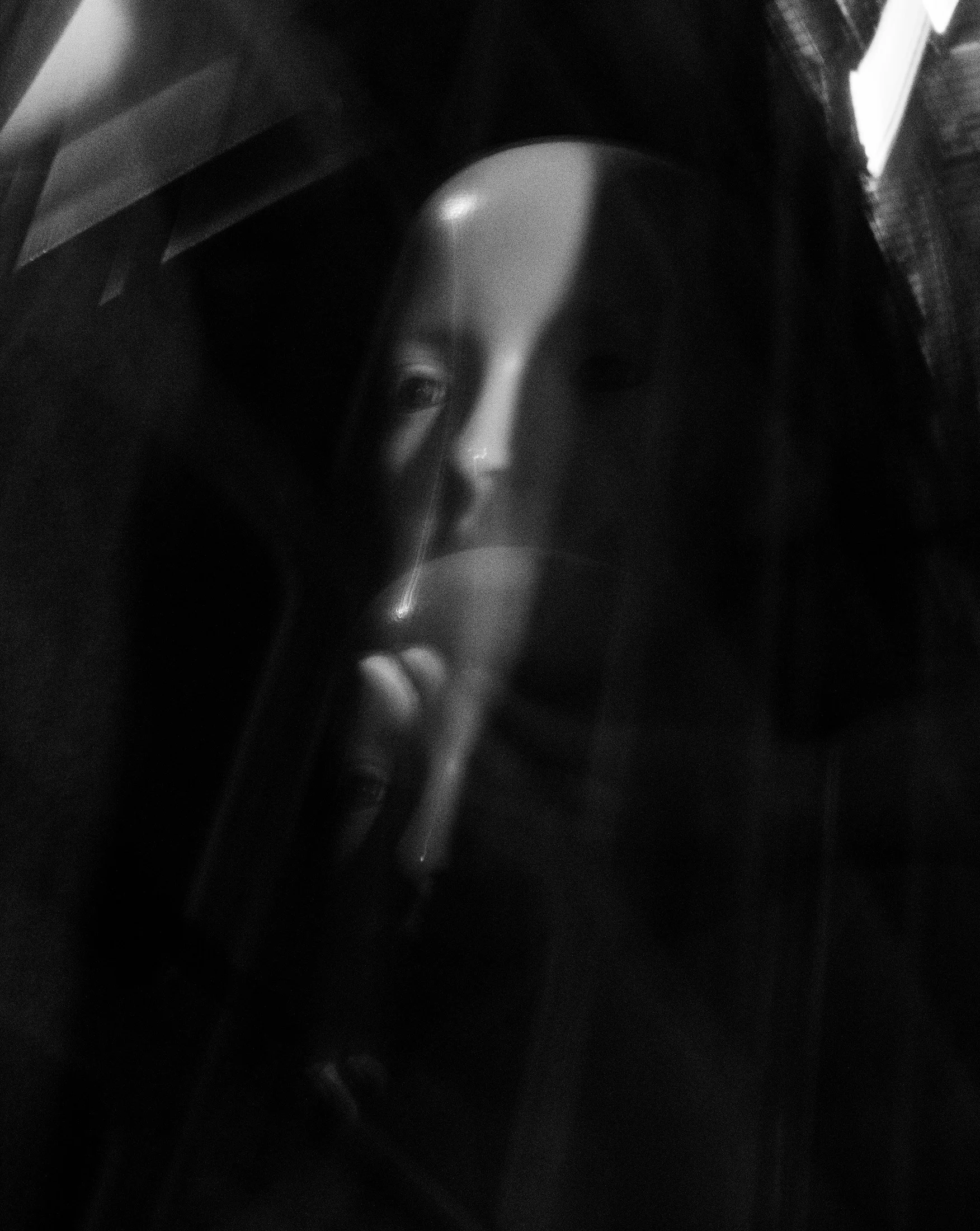 Fotografia digital em preto e branco, integrante da Série Digital 1, de Sandra Unglert Fernandes, mostrando um rosto parcialmente oculto, translúcidos e efeitos de sobreposição luminosa.