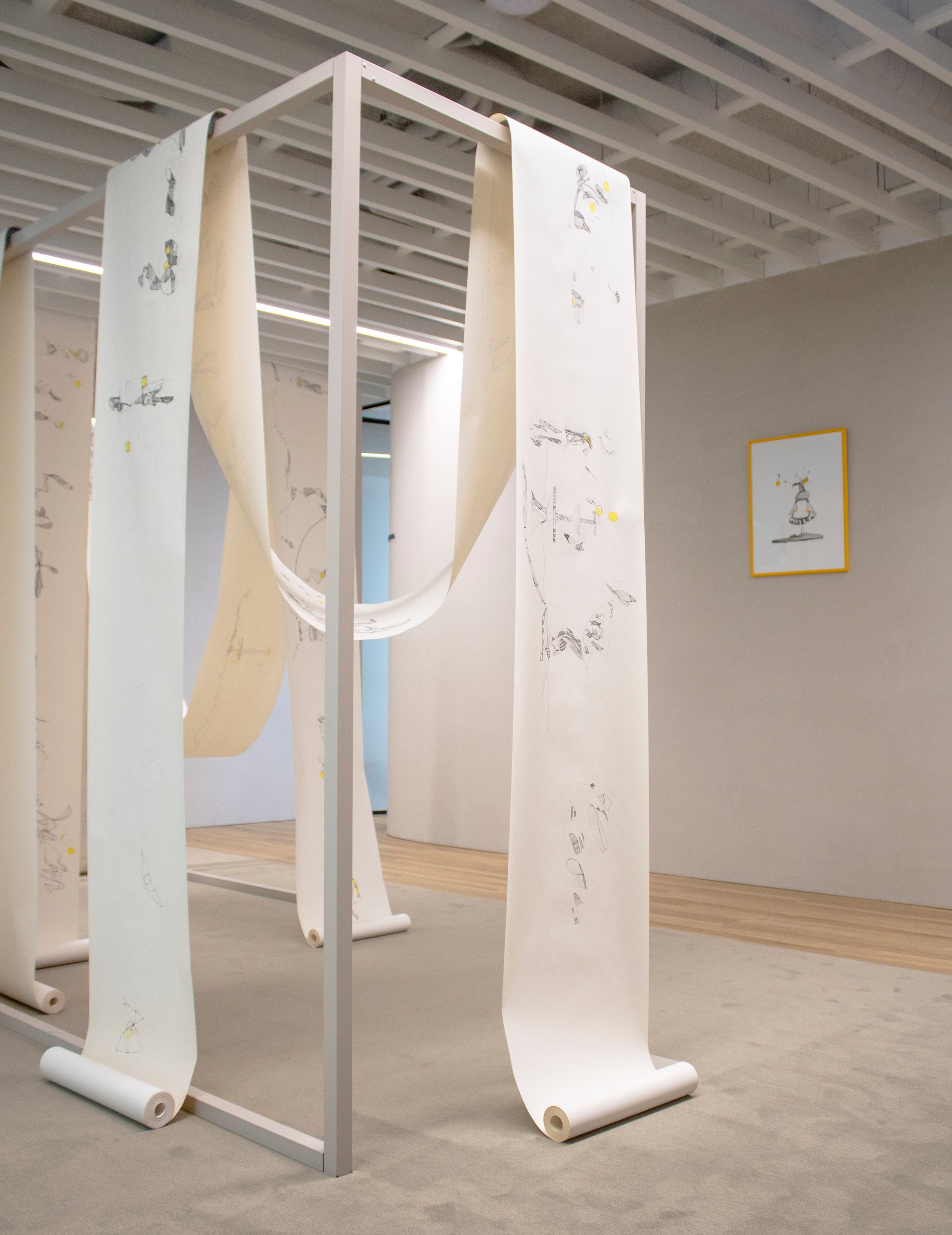 Vista da exposição Humanas Conexões, de Sandra Unglert Fernandes, mostrando os quatro rolos contínuos de desenho suspensos na instalação.