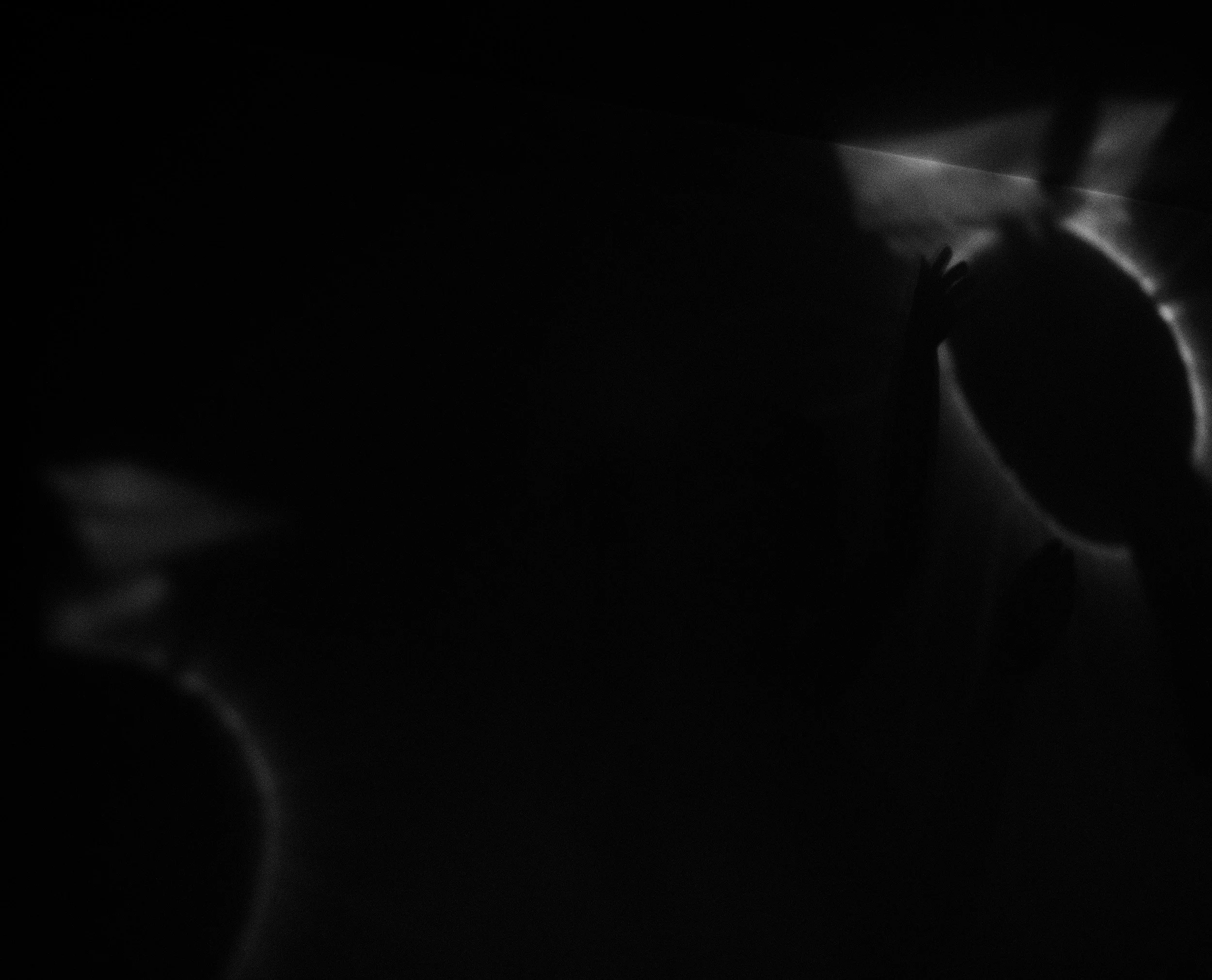 Fotografia digital em preto e branco, integrante da Série Digital 2, de Sandra Unglert Fernandes, mostrando silhuetas e halos luminosos em uma composição abstrata de forte contraste.